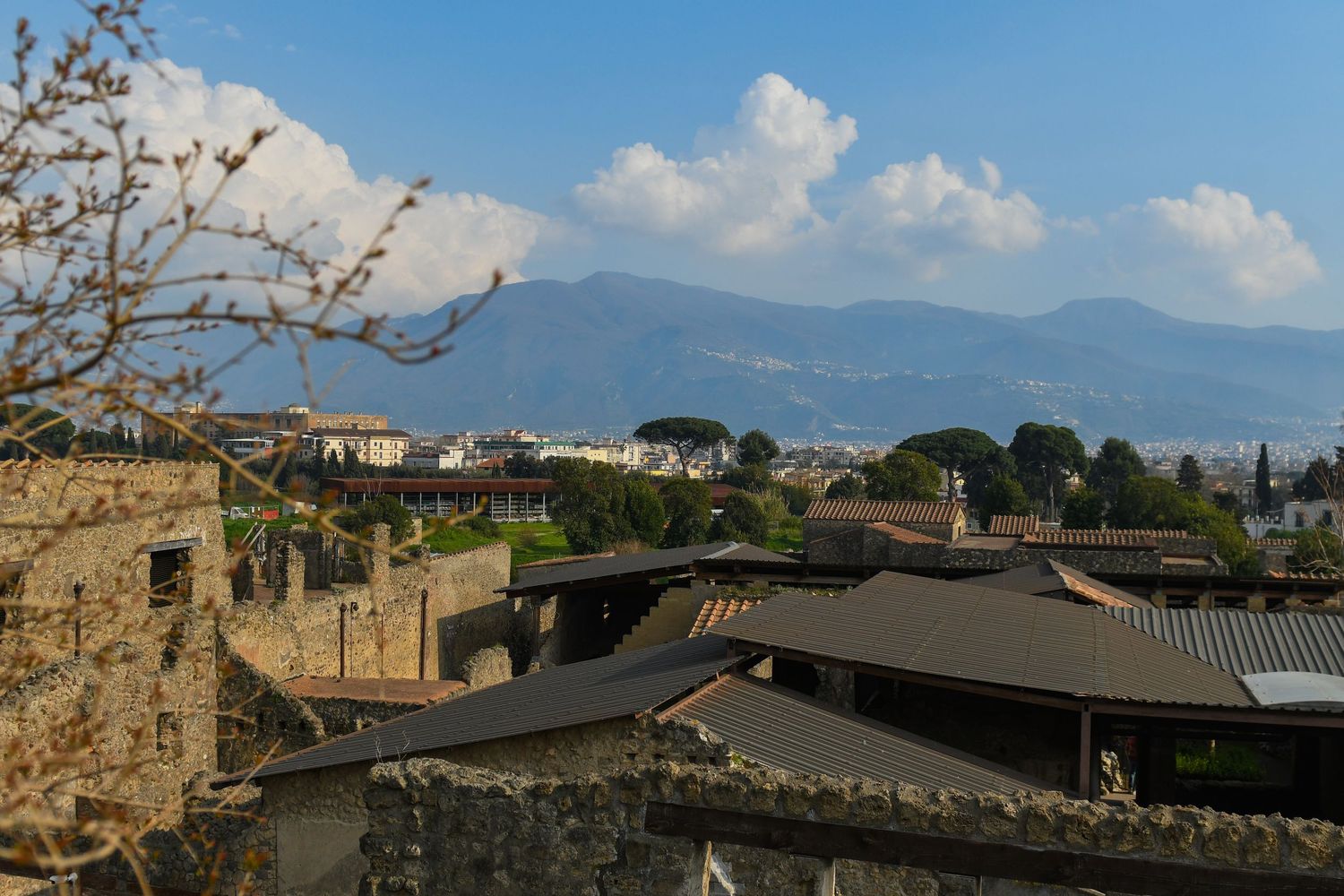 Panoramic view of Pompeii's rooftops and buildings with Mount Vesuvius visible in the background.