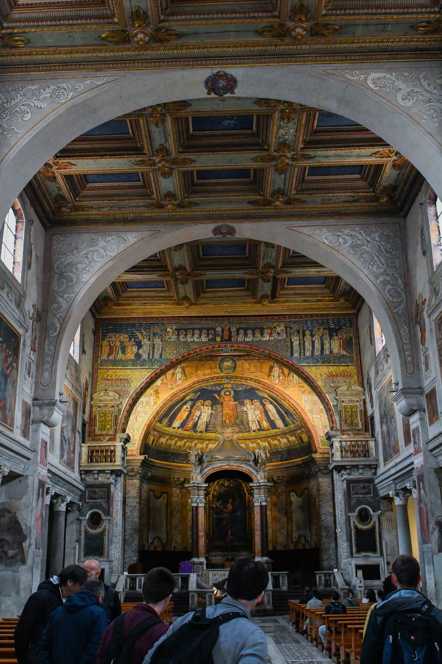Interior of historic church with ornate ceiling, arches, and religious artwork in the apse.