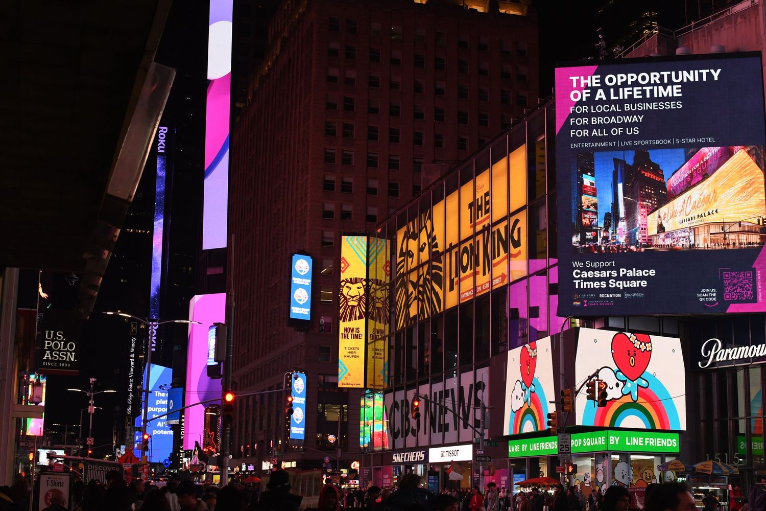 Times Square at night illuminated by bright colorful digital billboards and neon signs.