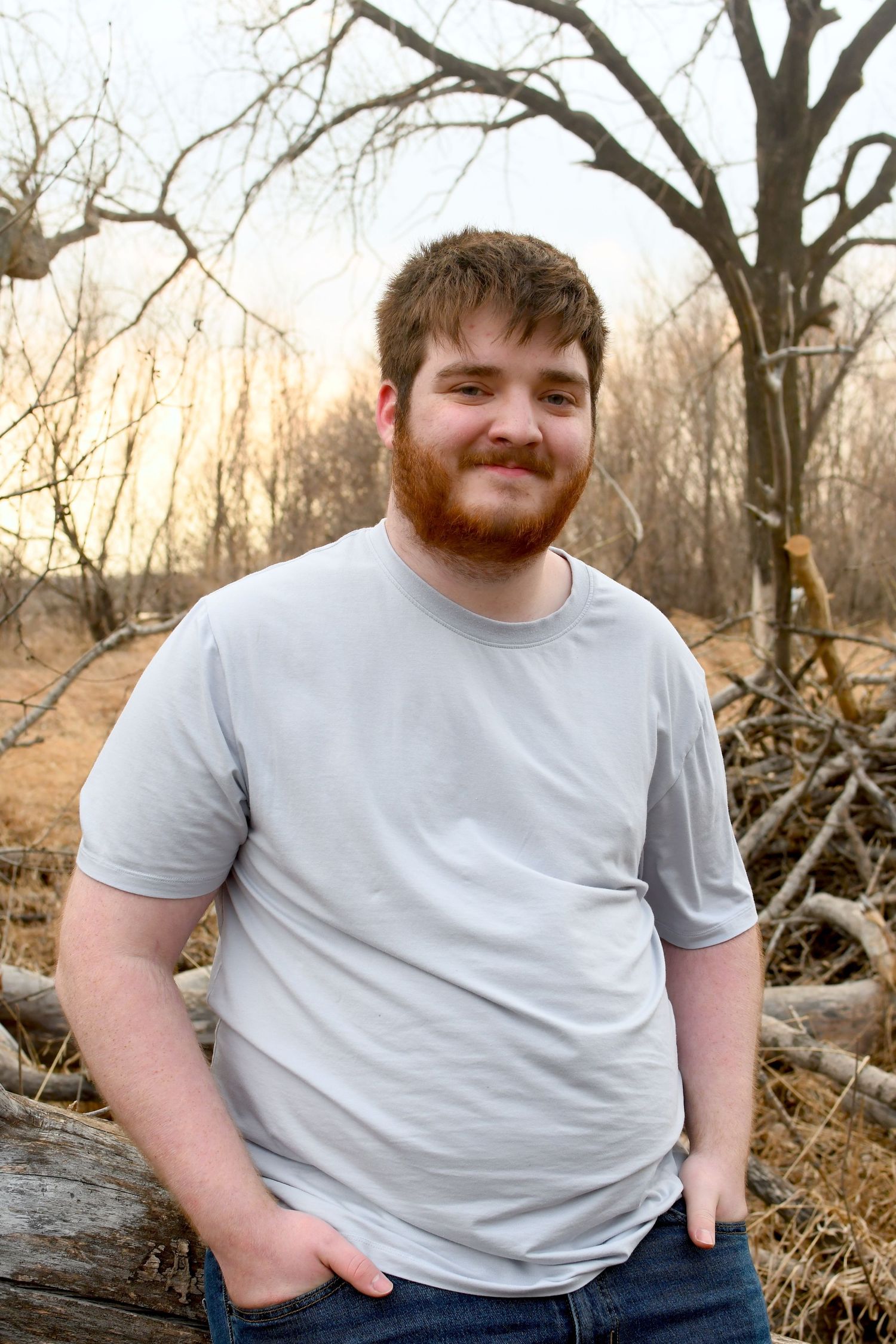 Winter outdoor portrait session in wooded setting with bare trees.