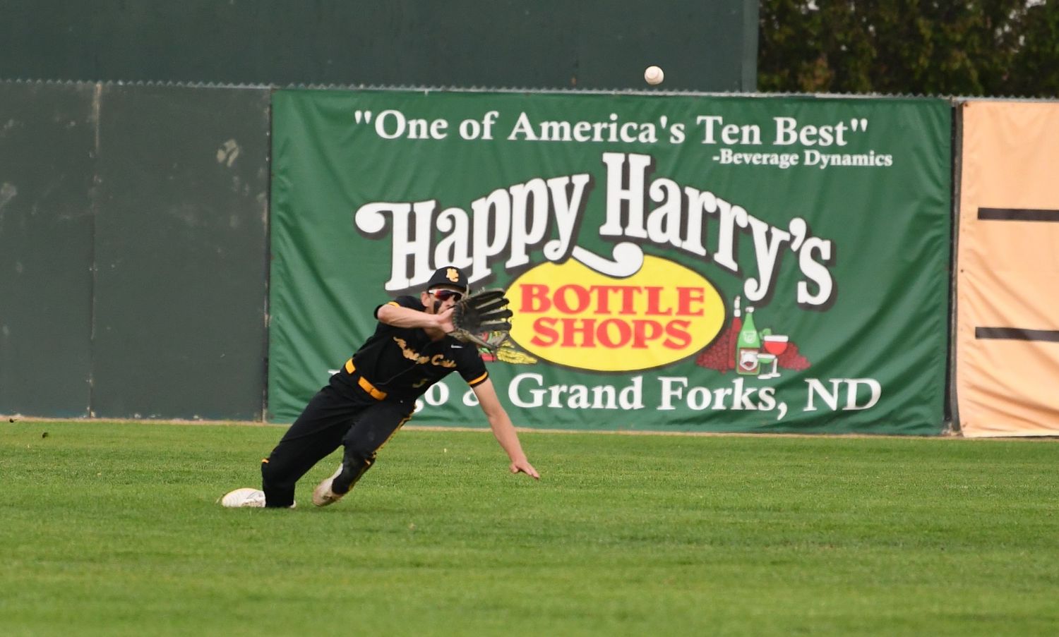 A baseball game in progress at a stadium with advertisements visible in the background.