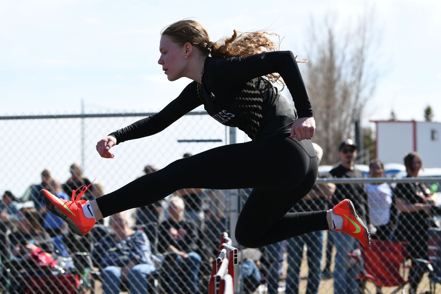 Long jumper soars through the air during competition at high school track meet.