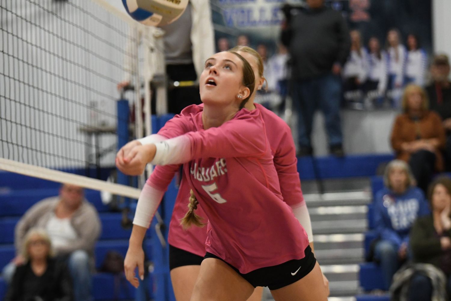 Volleyball player executes a powerful spike during a competitive match in a gymnasium.