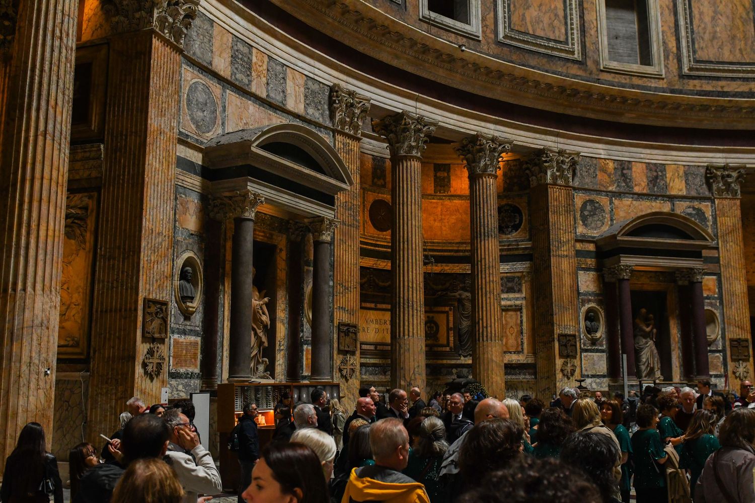 Interior view of the historic Pantheon in Rome showing its grand dome and classical architecture with tourists.