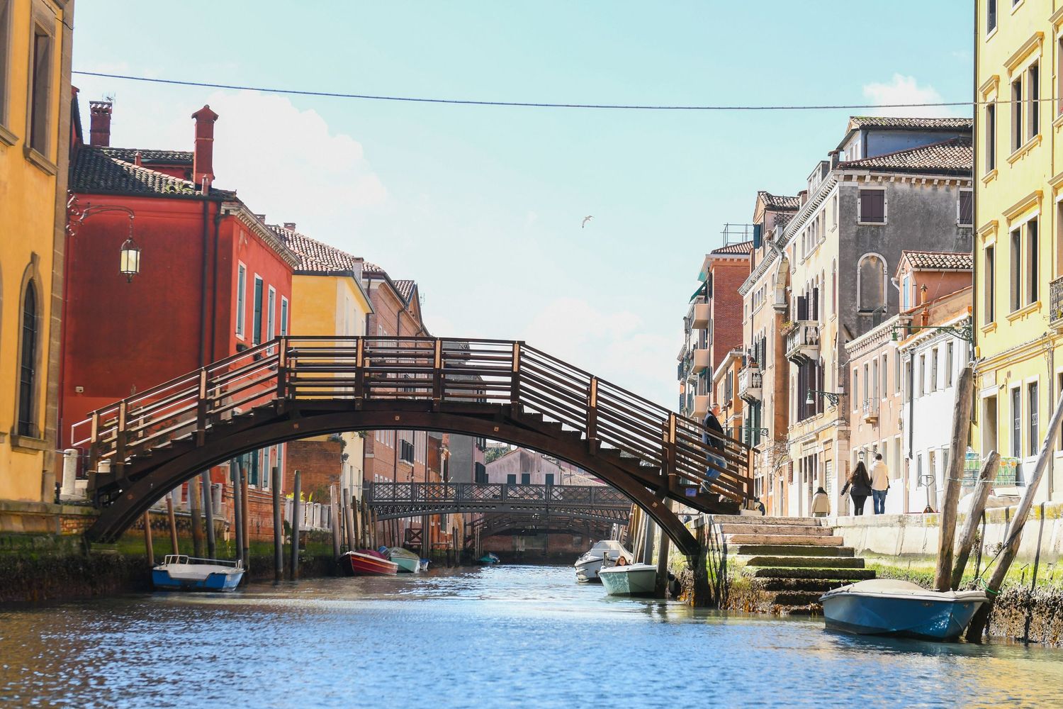 Historic buildings and bridges along Venice's canals reflect in the tranquil water.