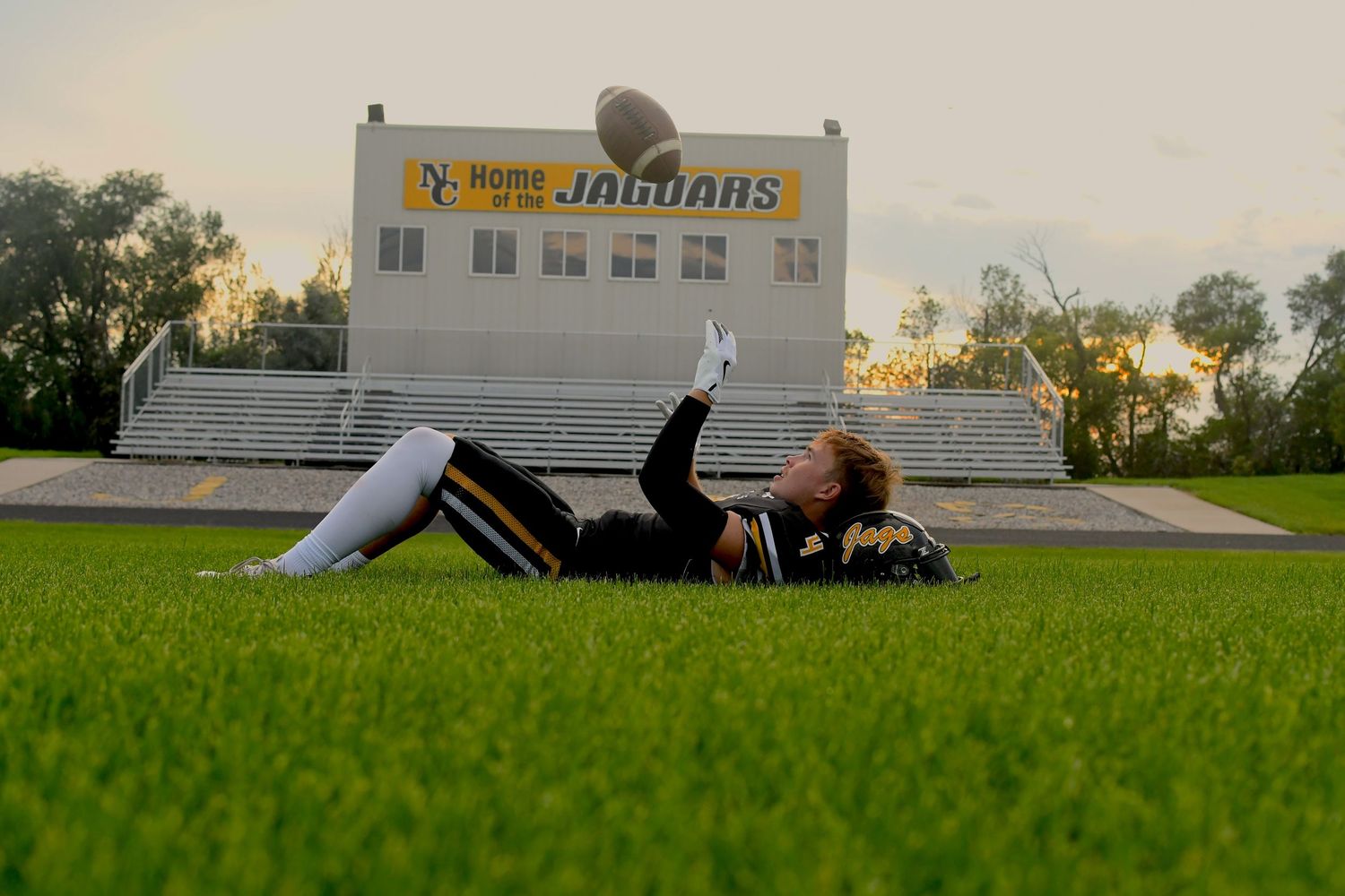 Low angle view of football field and bleachers during golden hour.