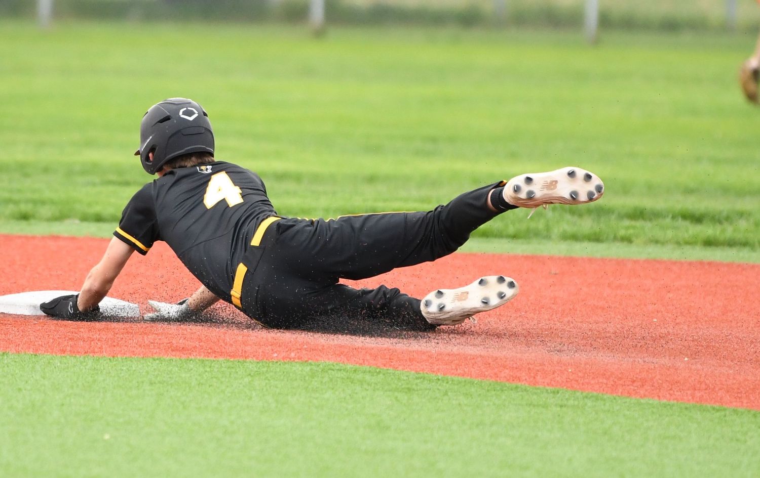 Baseball player slides on the red clay baseline during a game.
