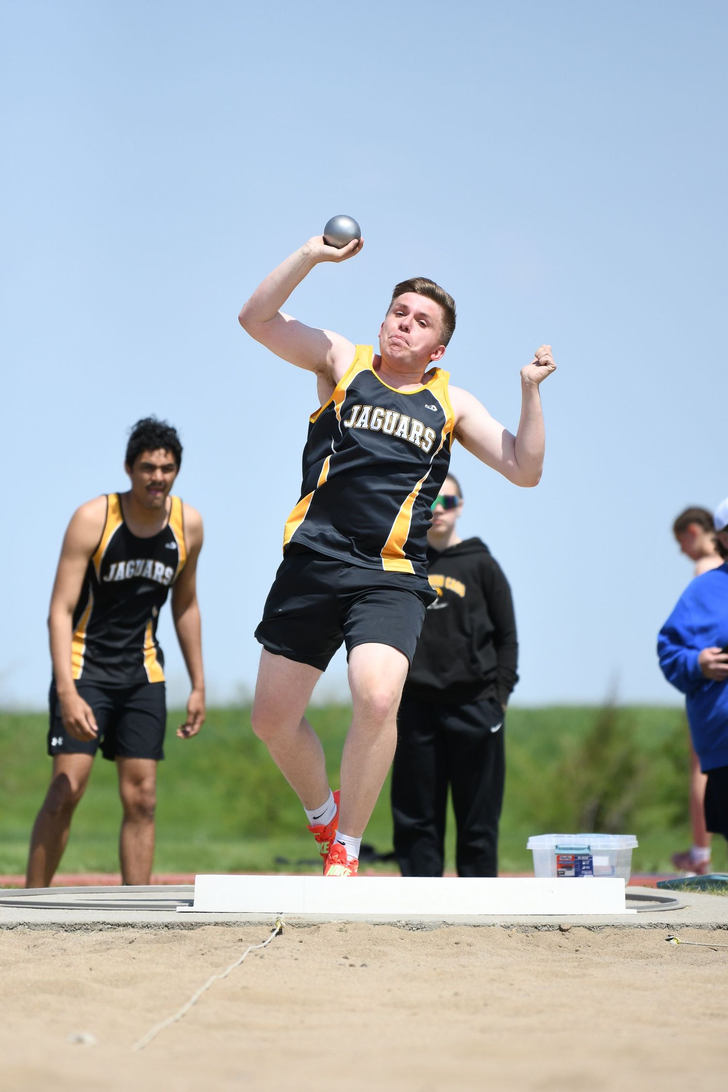 Track athletes compete in shot put event during outdoor competition.