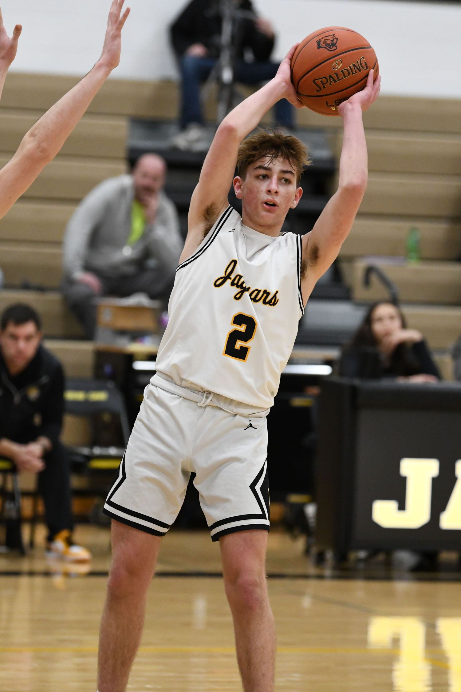 Basketball player in white Jaguars uniform looks to pass the ball during game play.