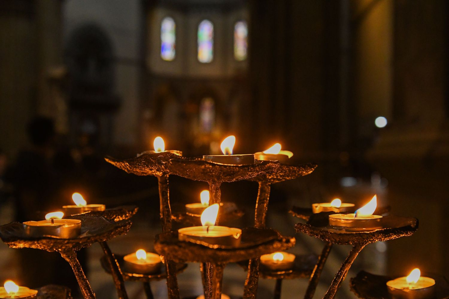 Row of glowing votive candles creating warm atmospheric lighting in a church interior.