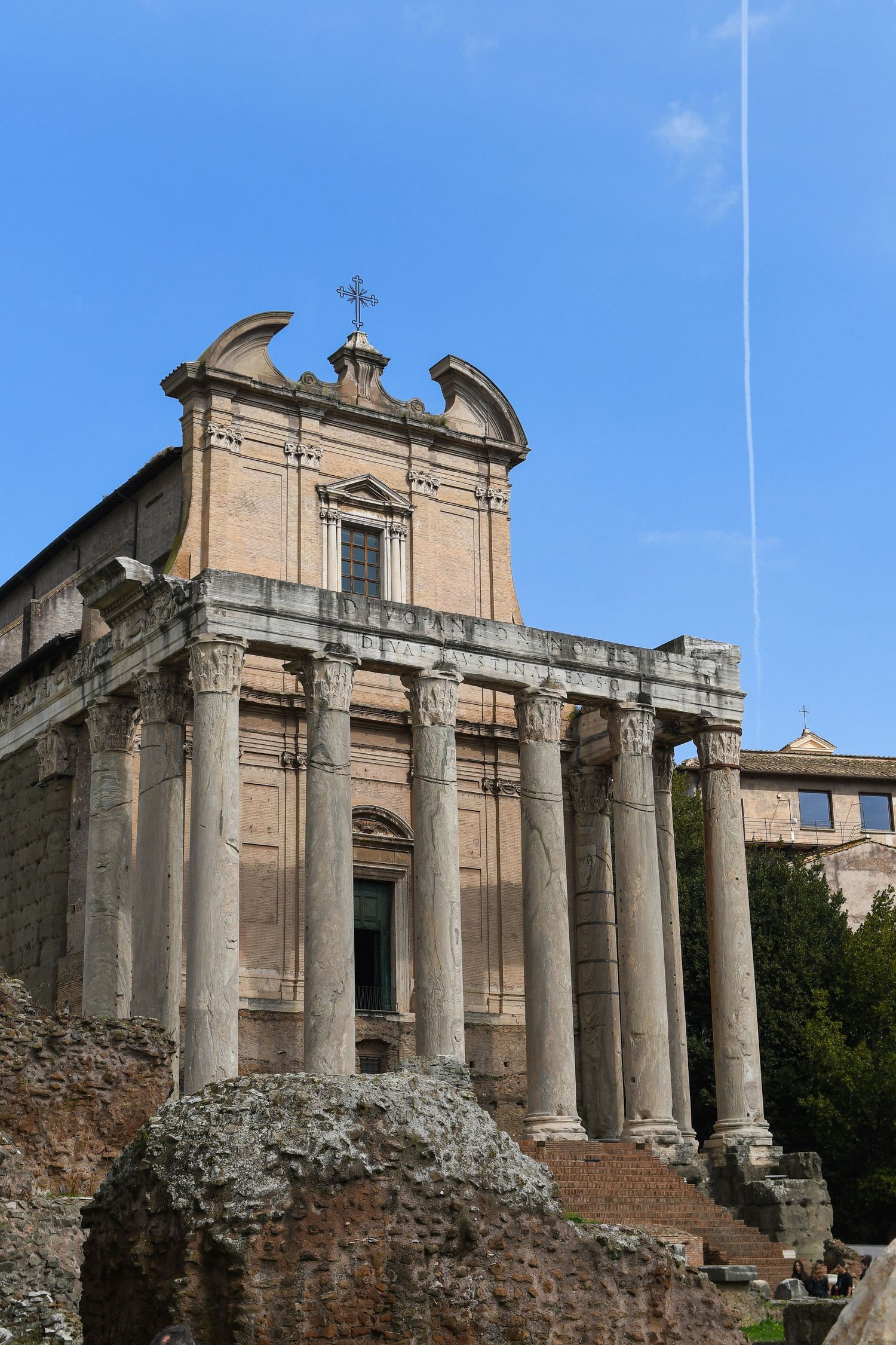 Ancient Roman ruins with stone columns and architectural remains against a bright blue sky.