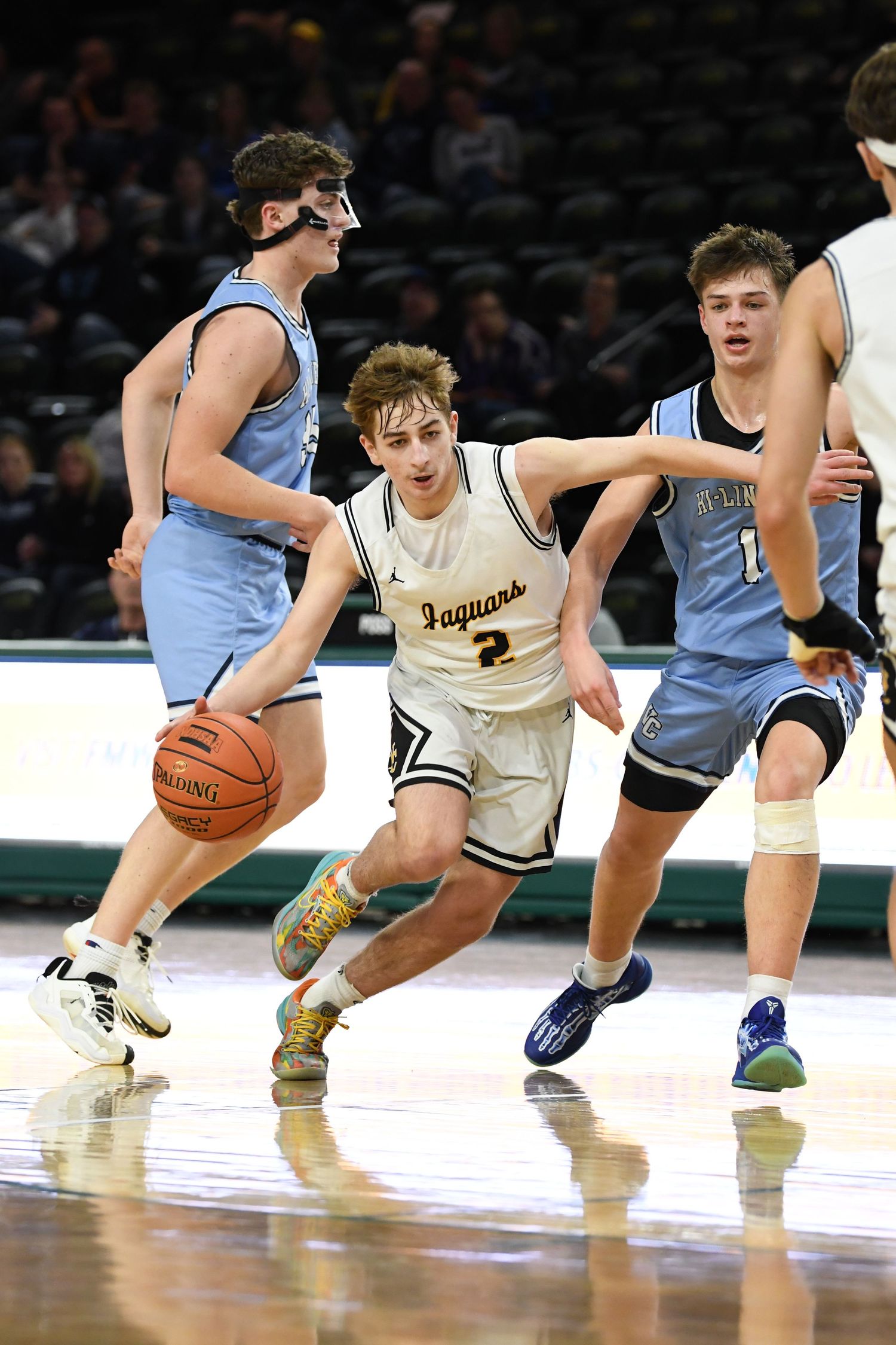 Basketball player attempts to navigate through defenders during competitive game.