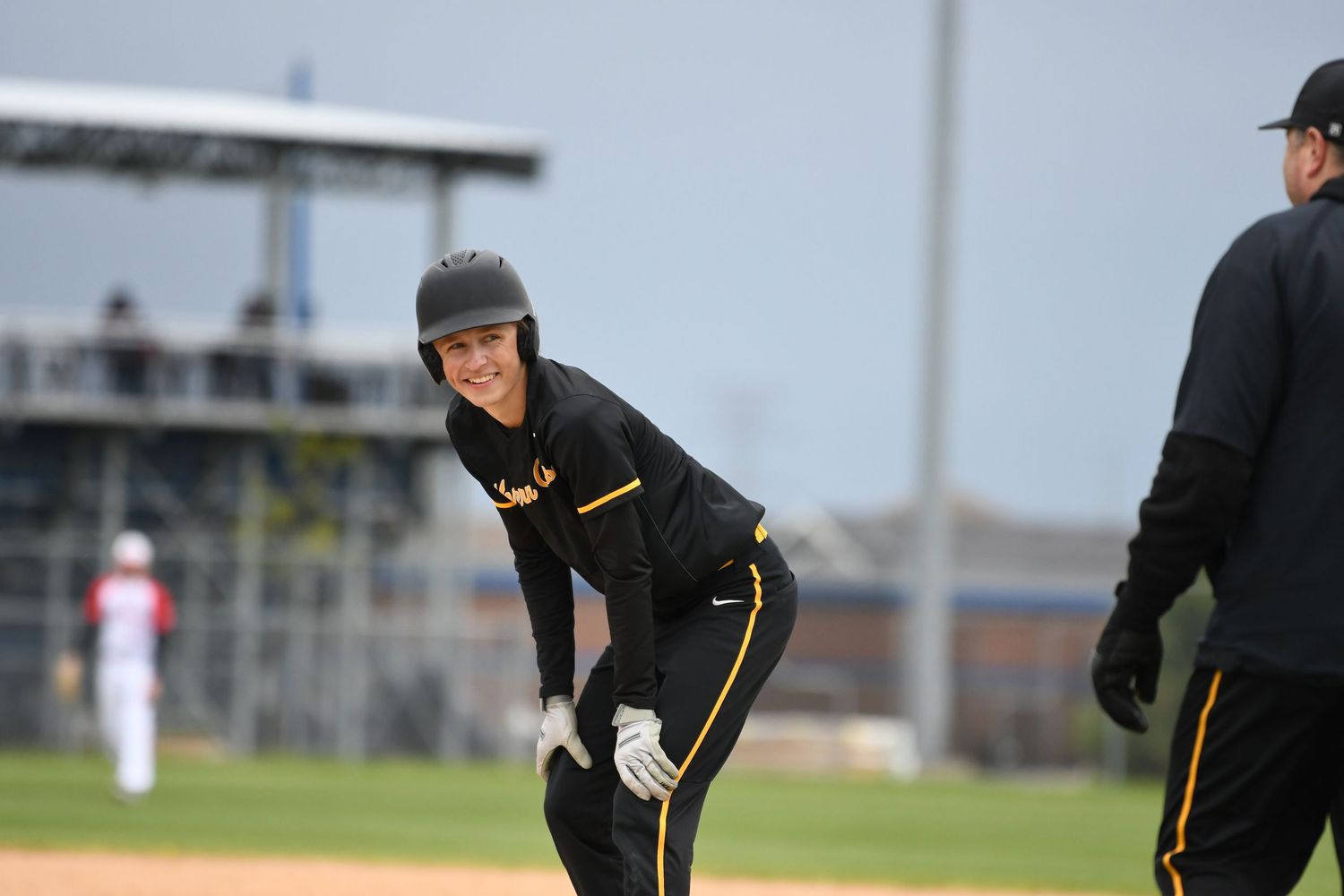 Baseball players in dark uniforms positioned during game near brick building.