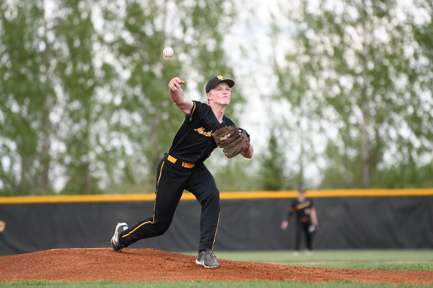 Baseball pitcher in black uniform throws from the mound during a game.