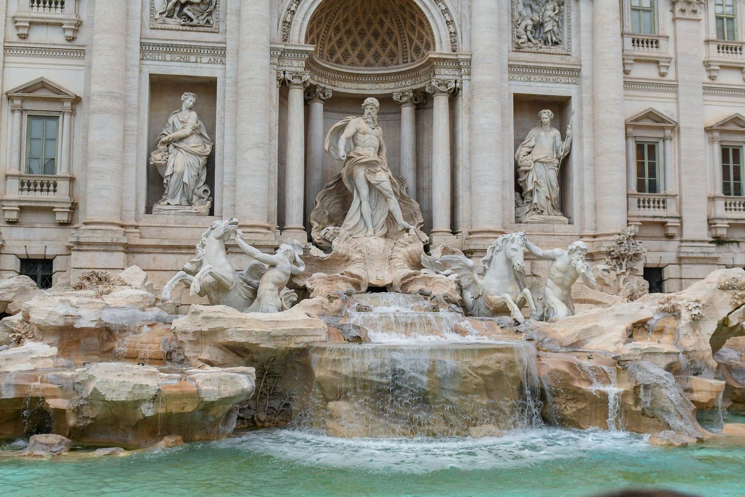 Panoramic view of the ornate Trevi Fountain with flowing water and baroque architecture.
