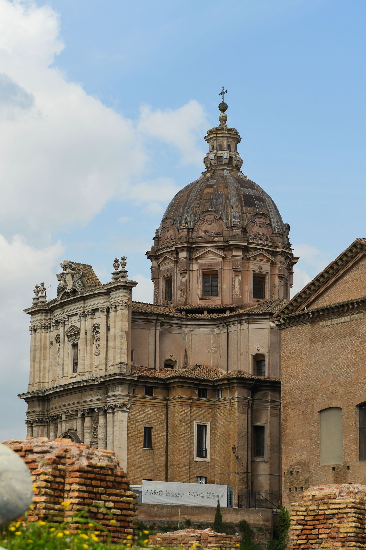 Ancient Roman ruins with domed church buildings and brick architecture against blue sky.