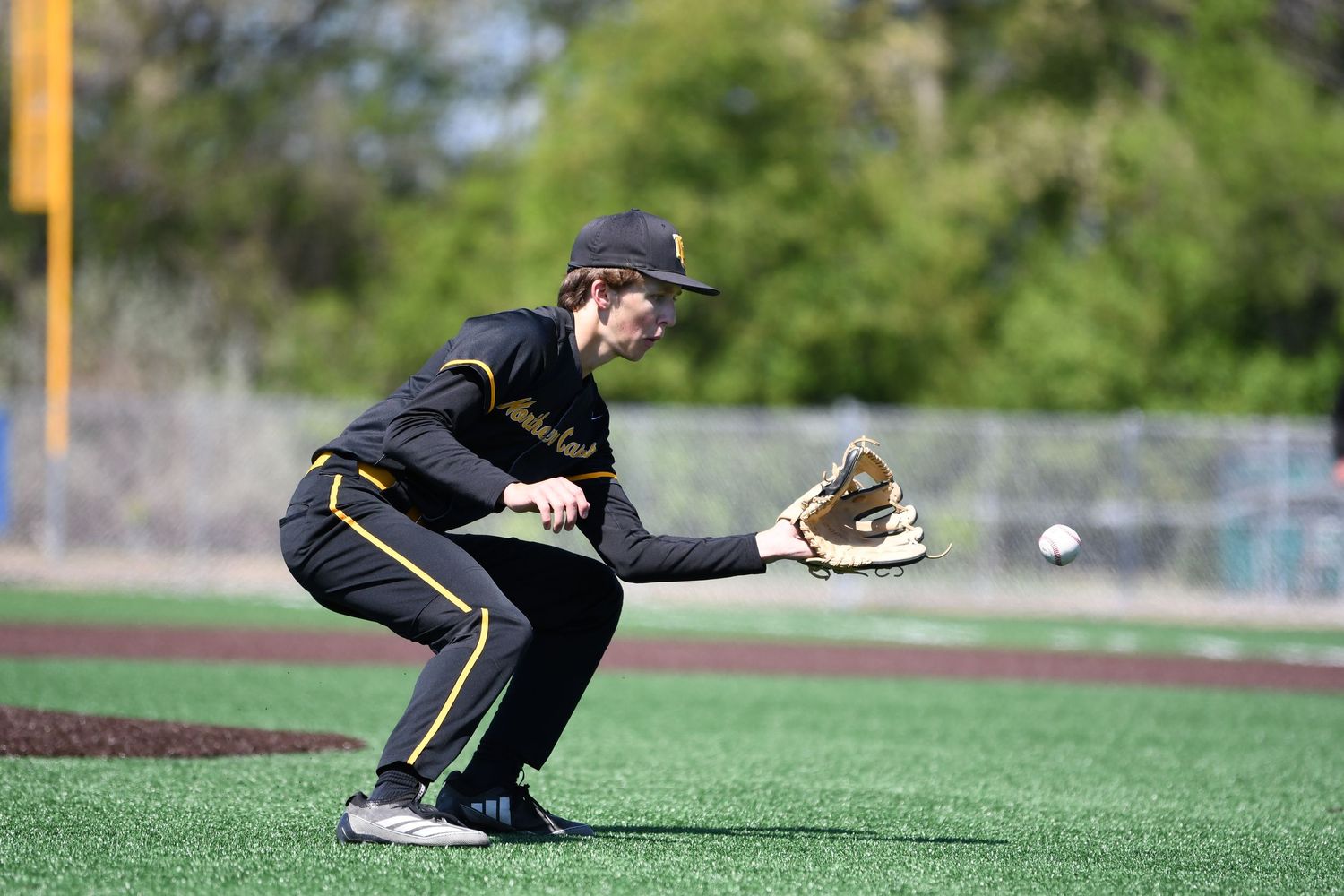 Baseball infielder crouches low in fielding position on the infield dirt.