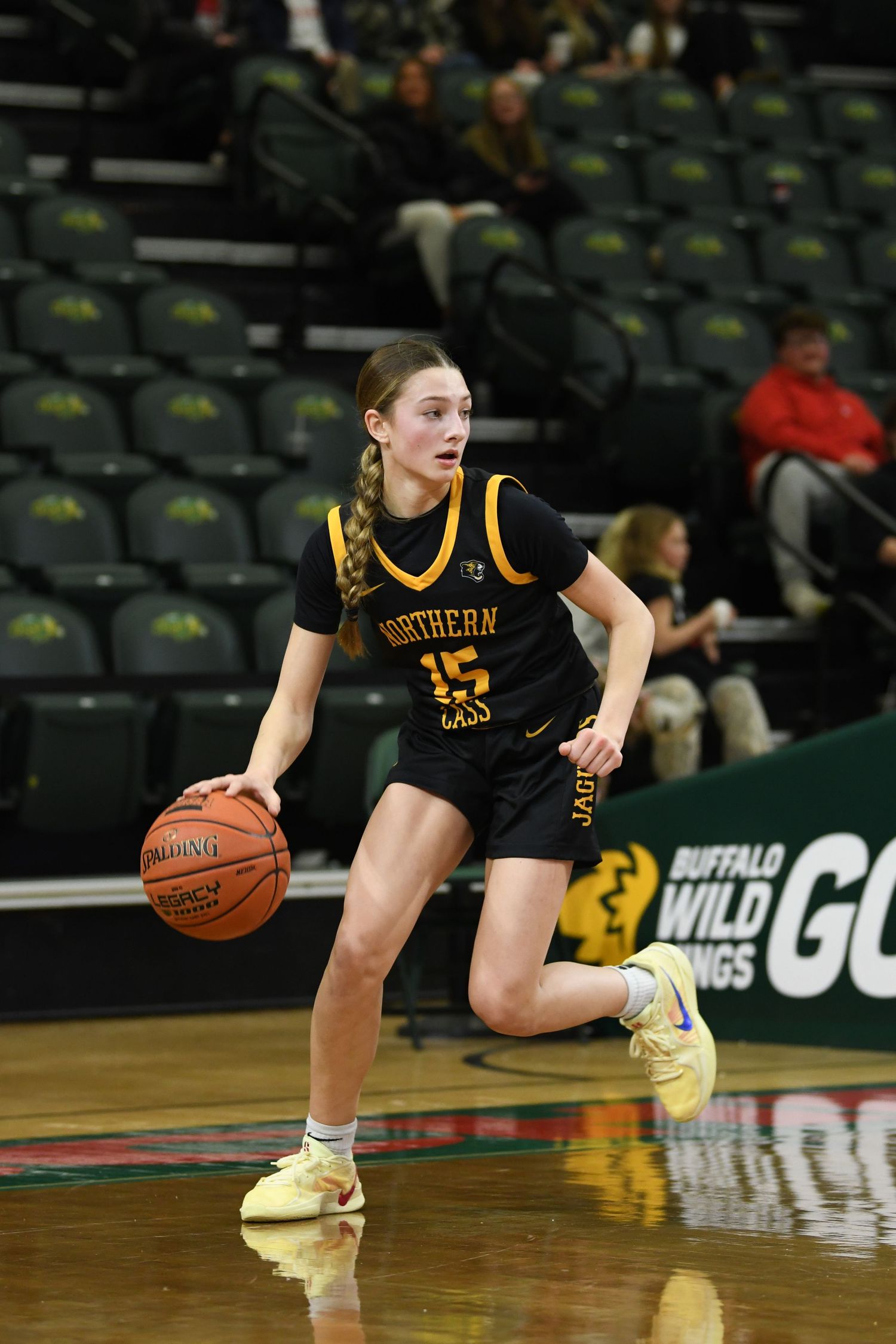 Basketball player in black jersey dribbles on court during game.