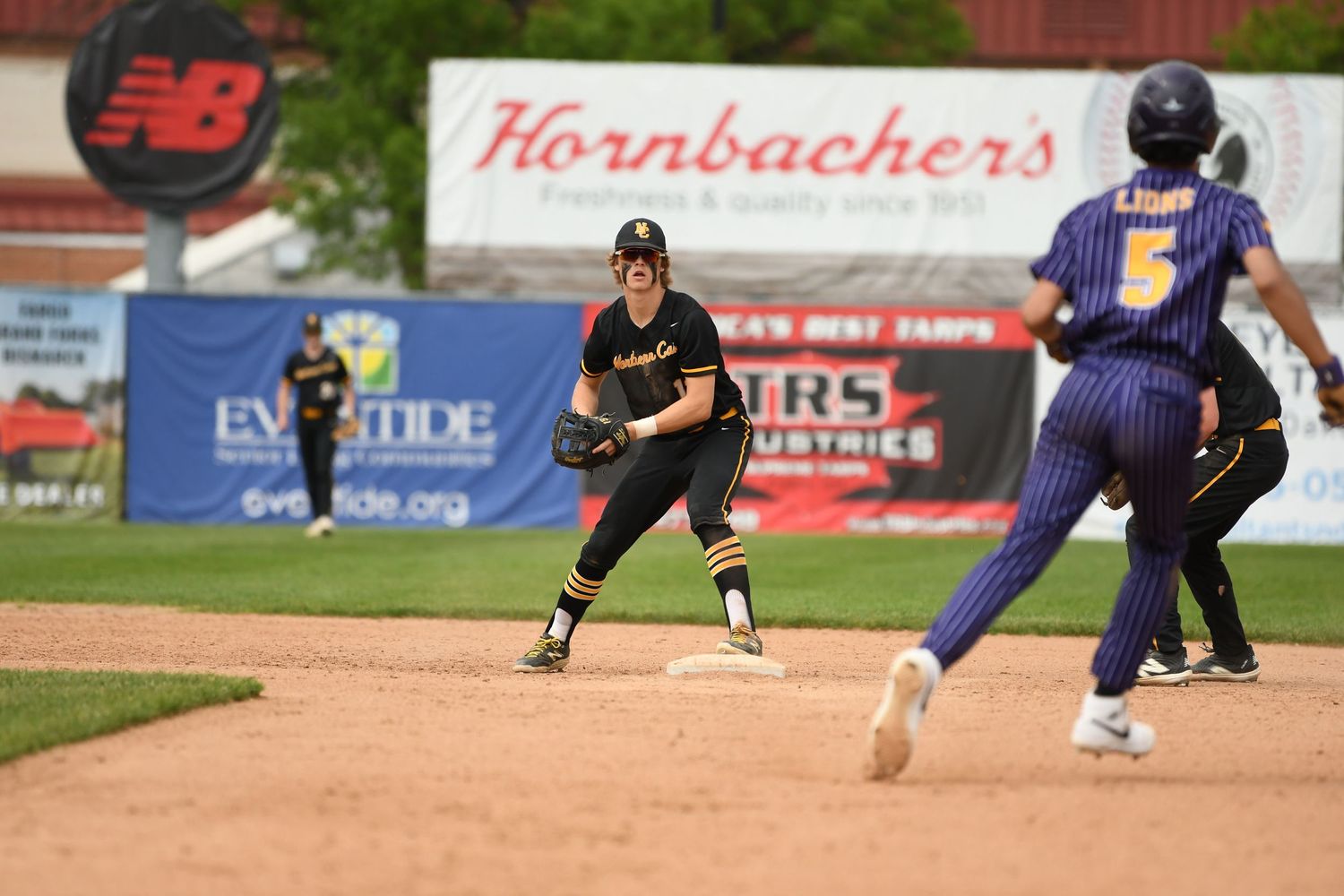 Baseball infield action shows players from opposing teams during game play.