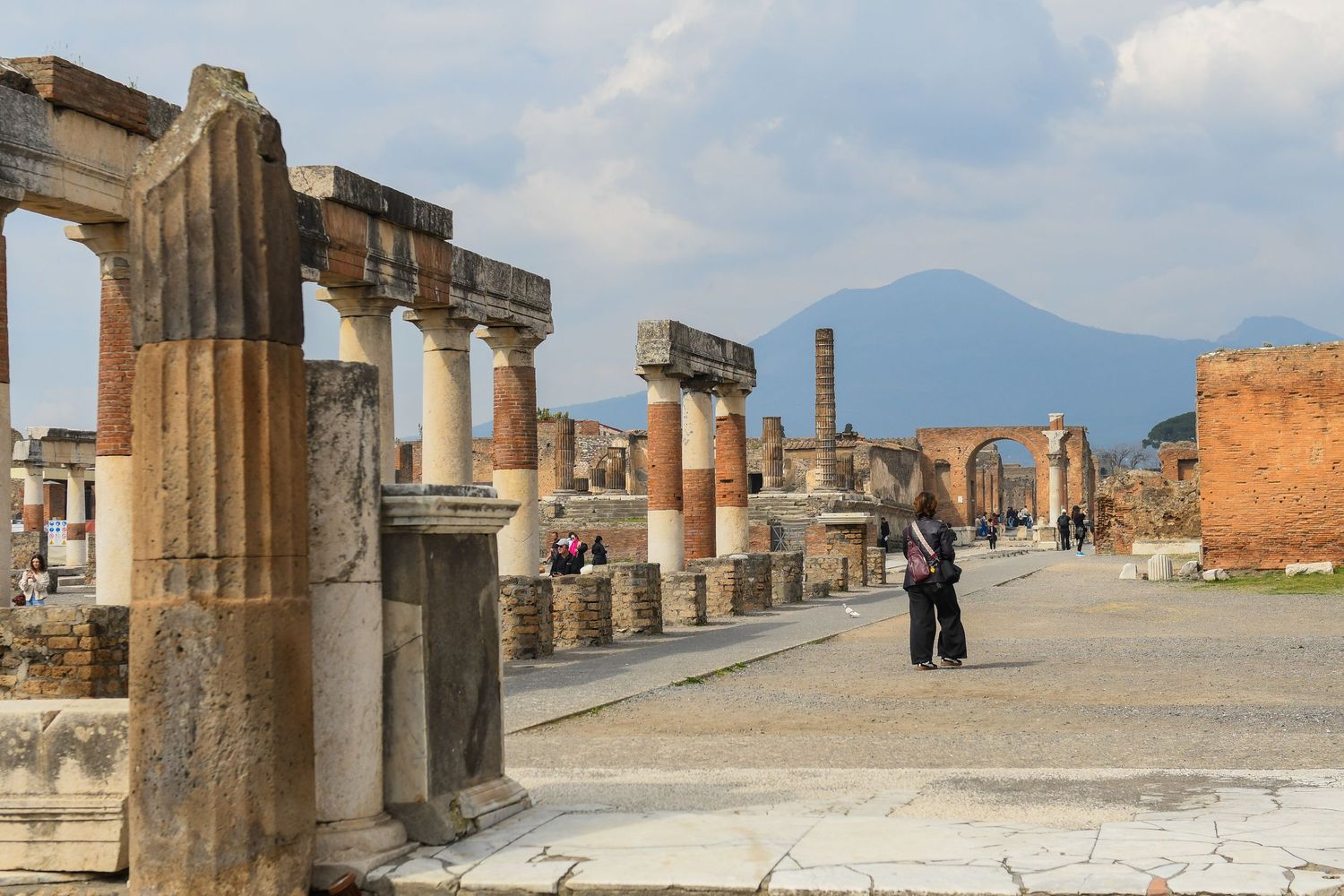 Panoramic view of Pompeii ruins with Mount Vesuvius visible in the distance.