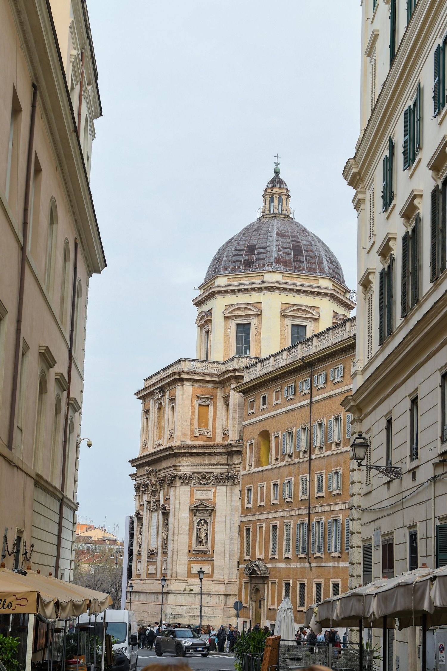 Historic domed church building with classical architecture visible between narrow city streets in Rome.