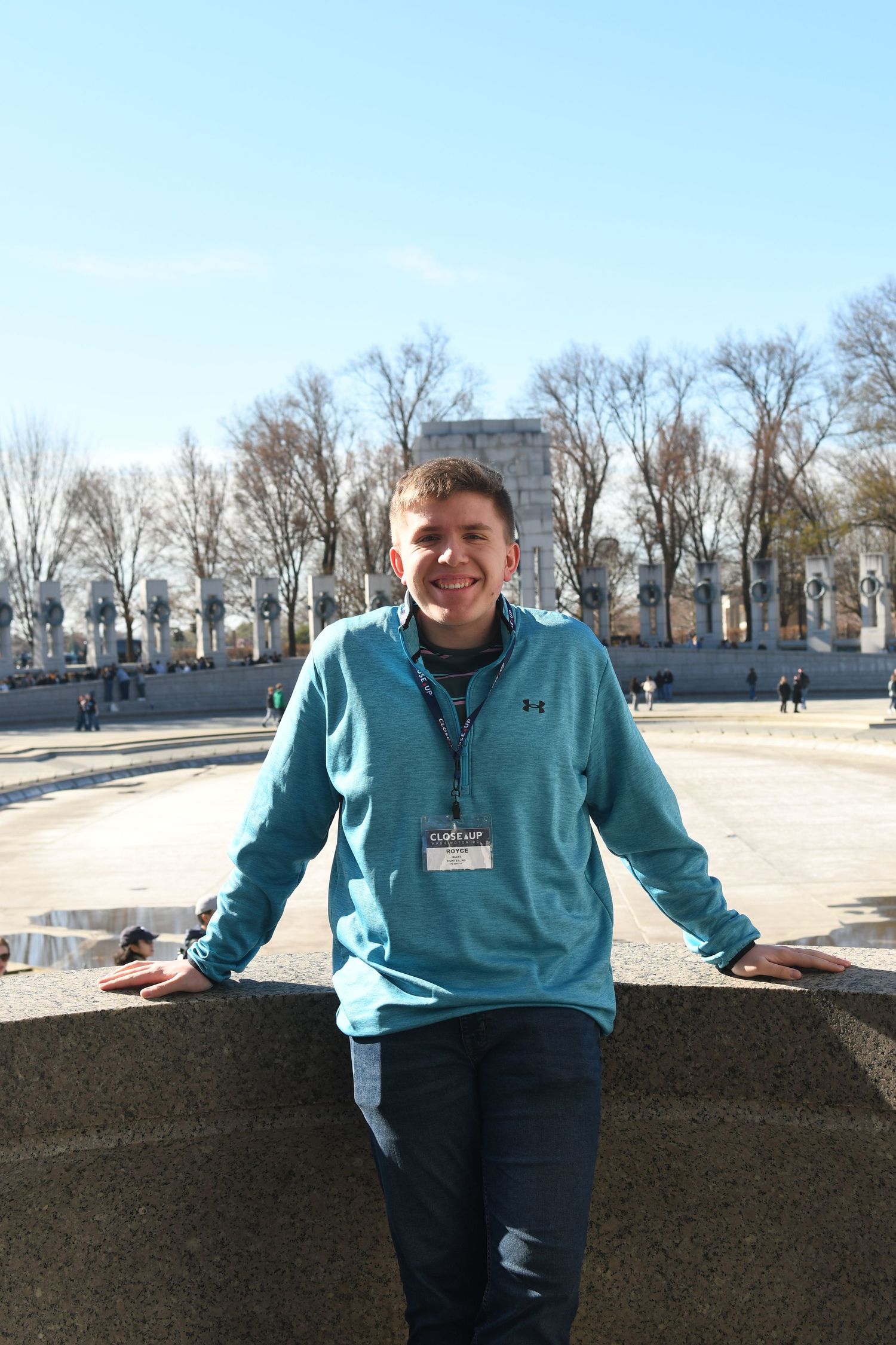 Person in light blue pullover standing against stone barrier at historic monument.