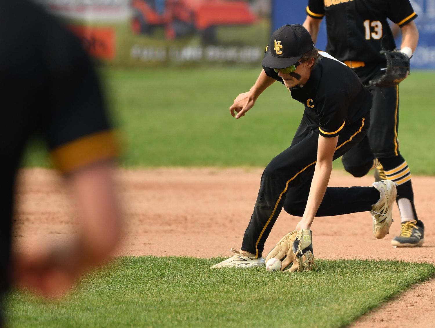 Baseball player fielding ground ball during game while wearing black and gold uniform.