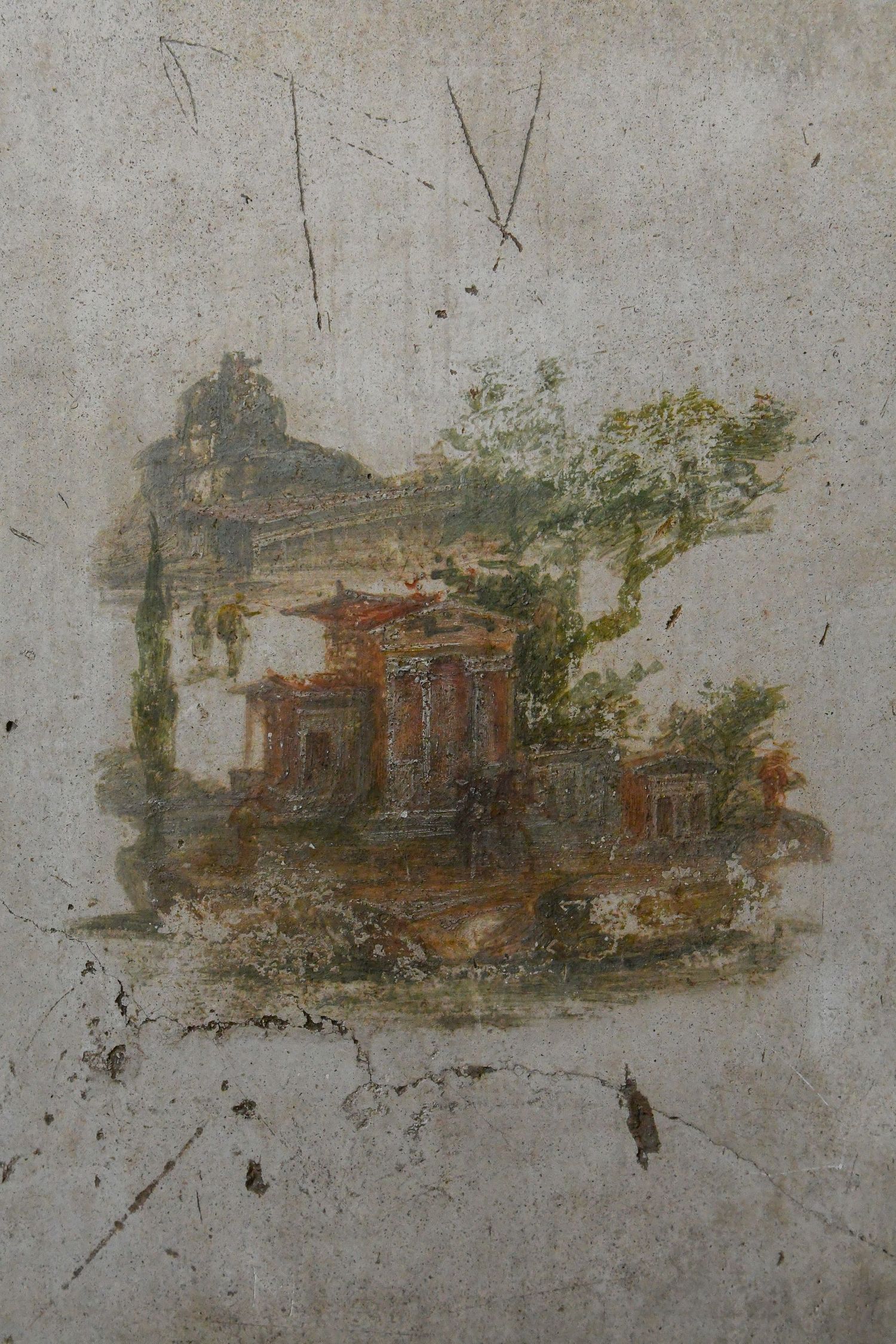 Faded Roman fresco showing architectural landscape scenes painted on a weathered grey wall.