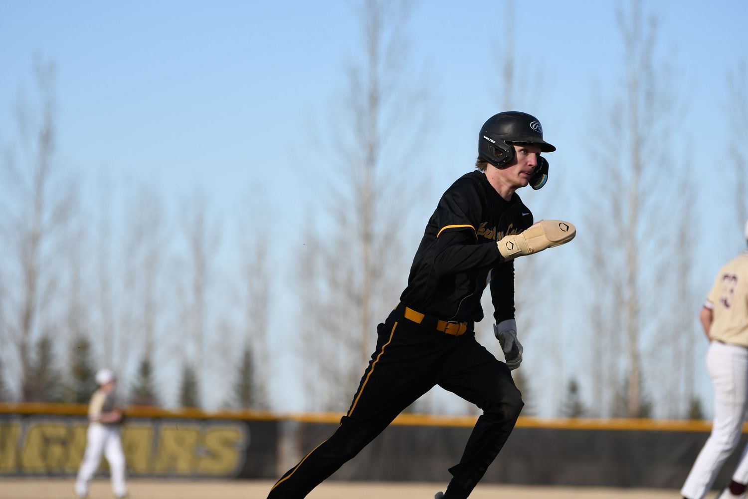 Baseball player in black uniform running between bases during competitive game.