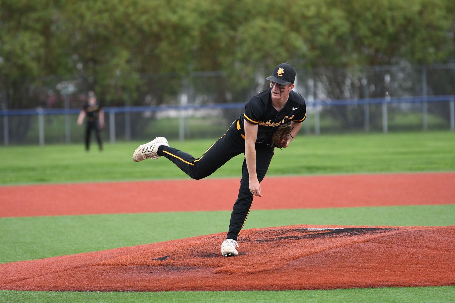 Pitcher follows through on delivery from the mound wearing black uniform.