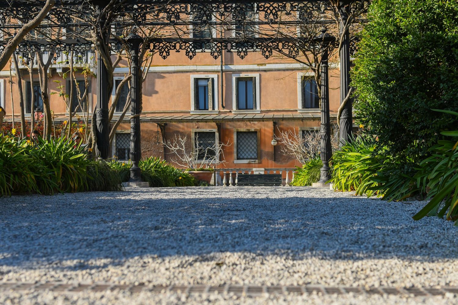 Gravel pathway leading through a garden with buildings visible in background.