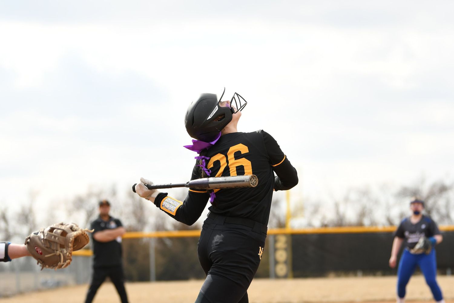Softball player in black uniform making defensive play on infield dirt.