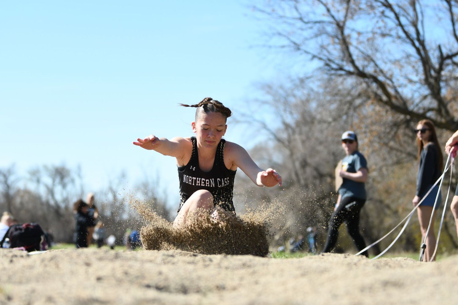 Athlete performing a long jump at an outdoor track and field event.