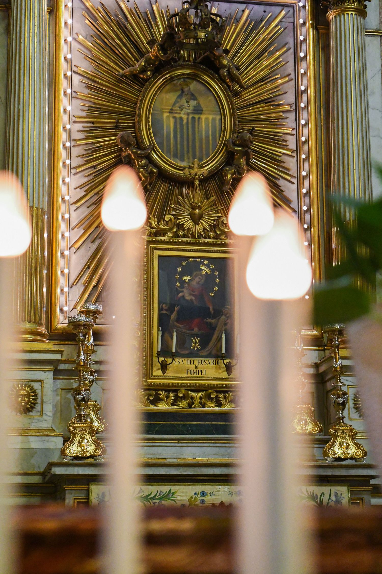 Ornate golden altar decorations with sunburst designs and religious artwork in a baroque church.