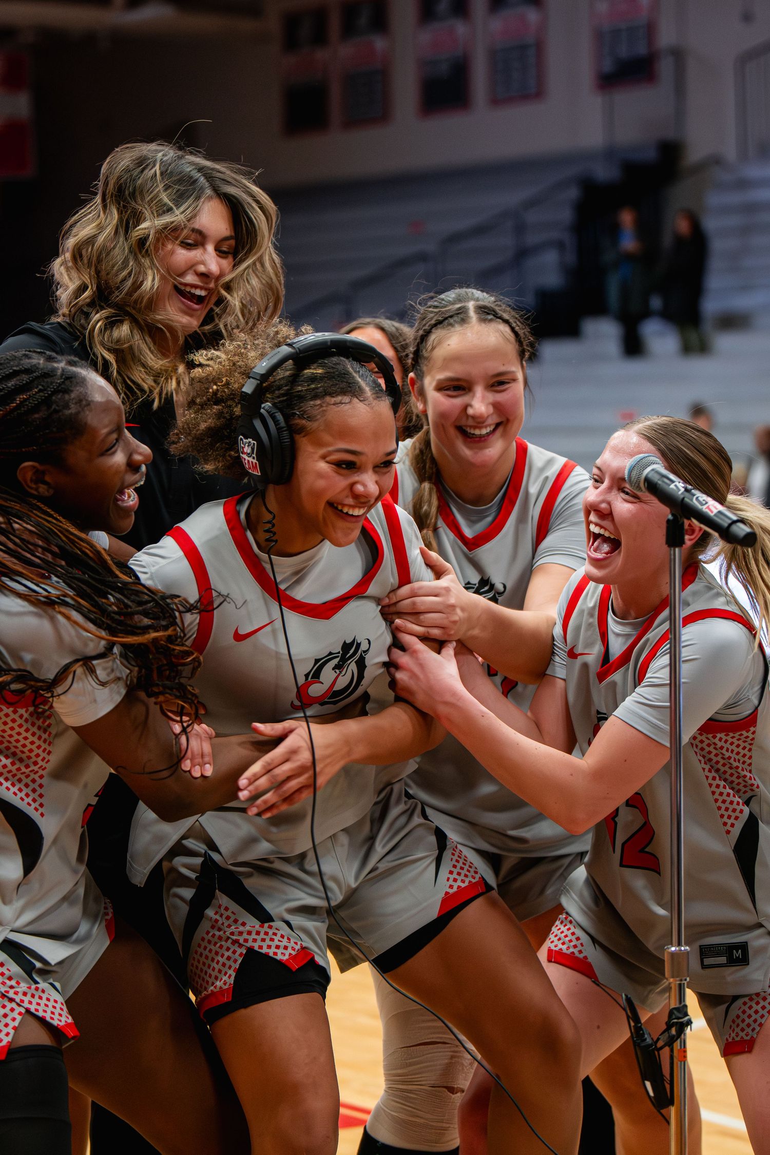 Athletes in red and white uniforms celebrate together with joyful expressions and embraces during a sporting event.