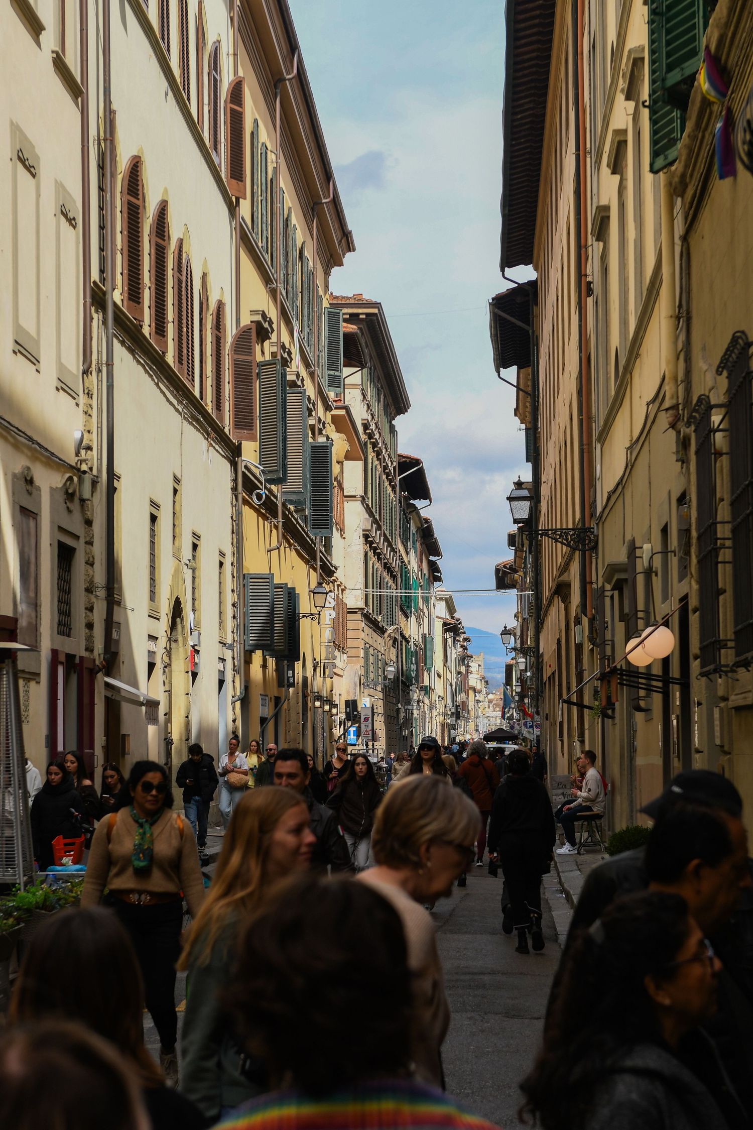 Narrow Italian street lined with historic buildings and filled with tourists.