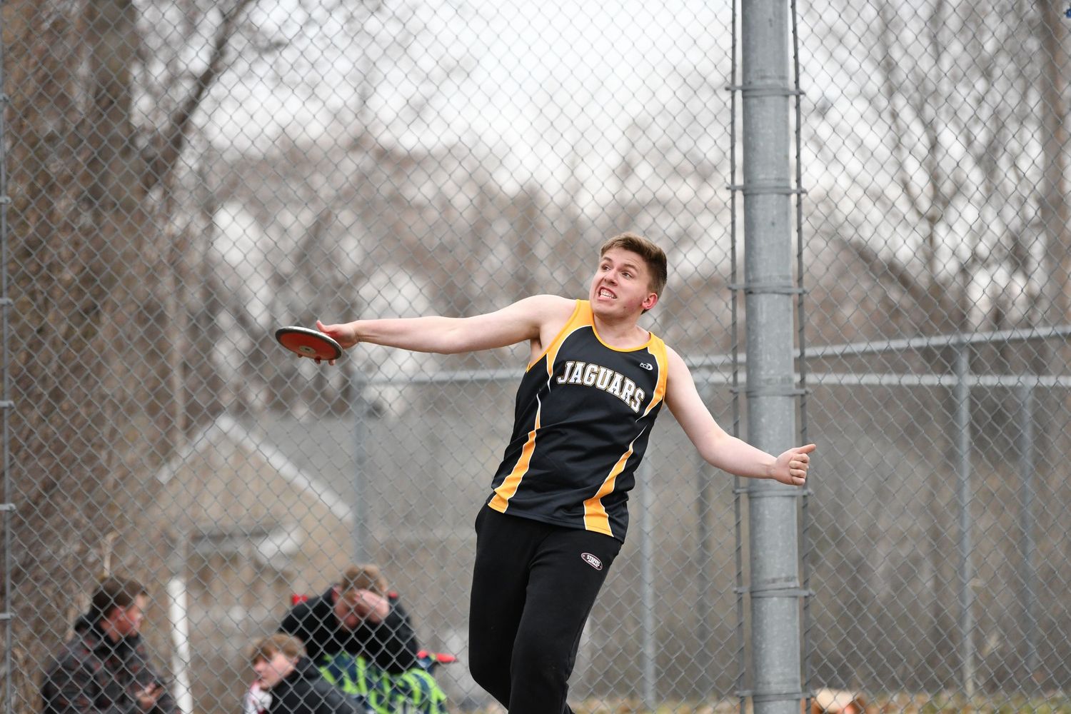 Athlete extends arms while performing long jump technique on outdoor track.