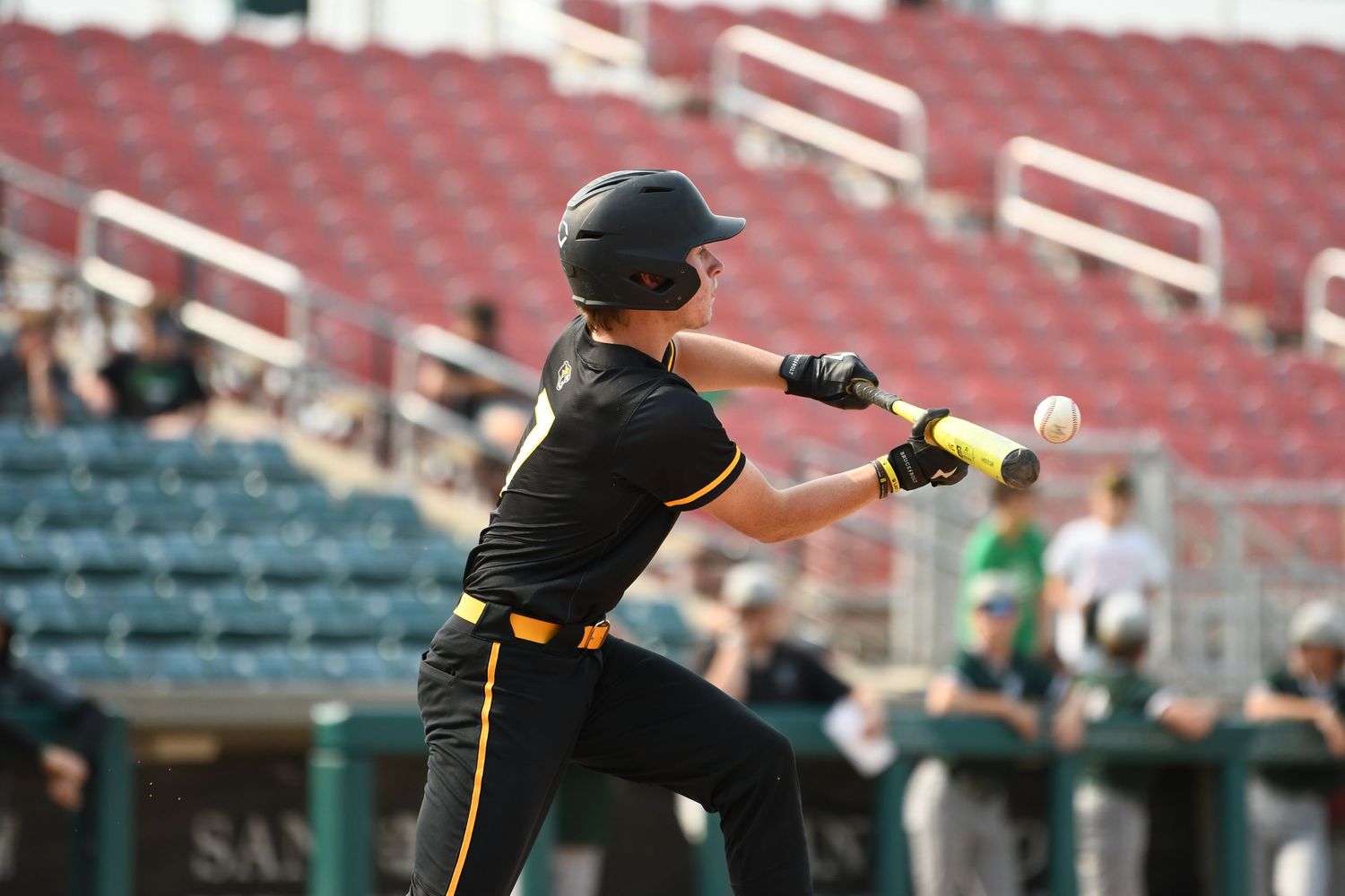 Baseball players practicing on a field with empty red stadium seats visible in the background.