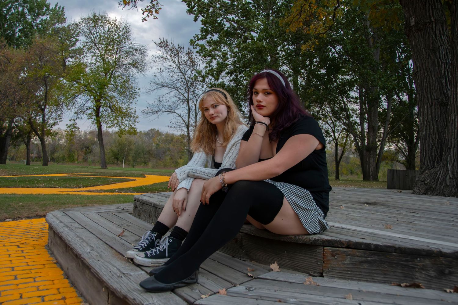 Two people sitting together on wooden steps outdoors on an autumn day with yellow painted edges.