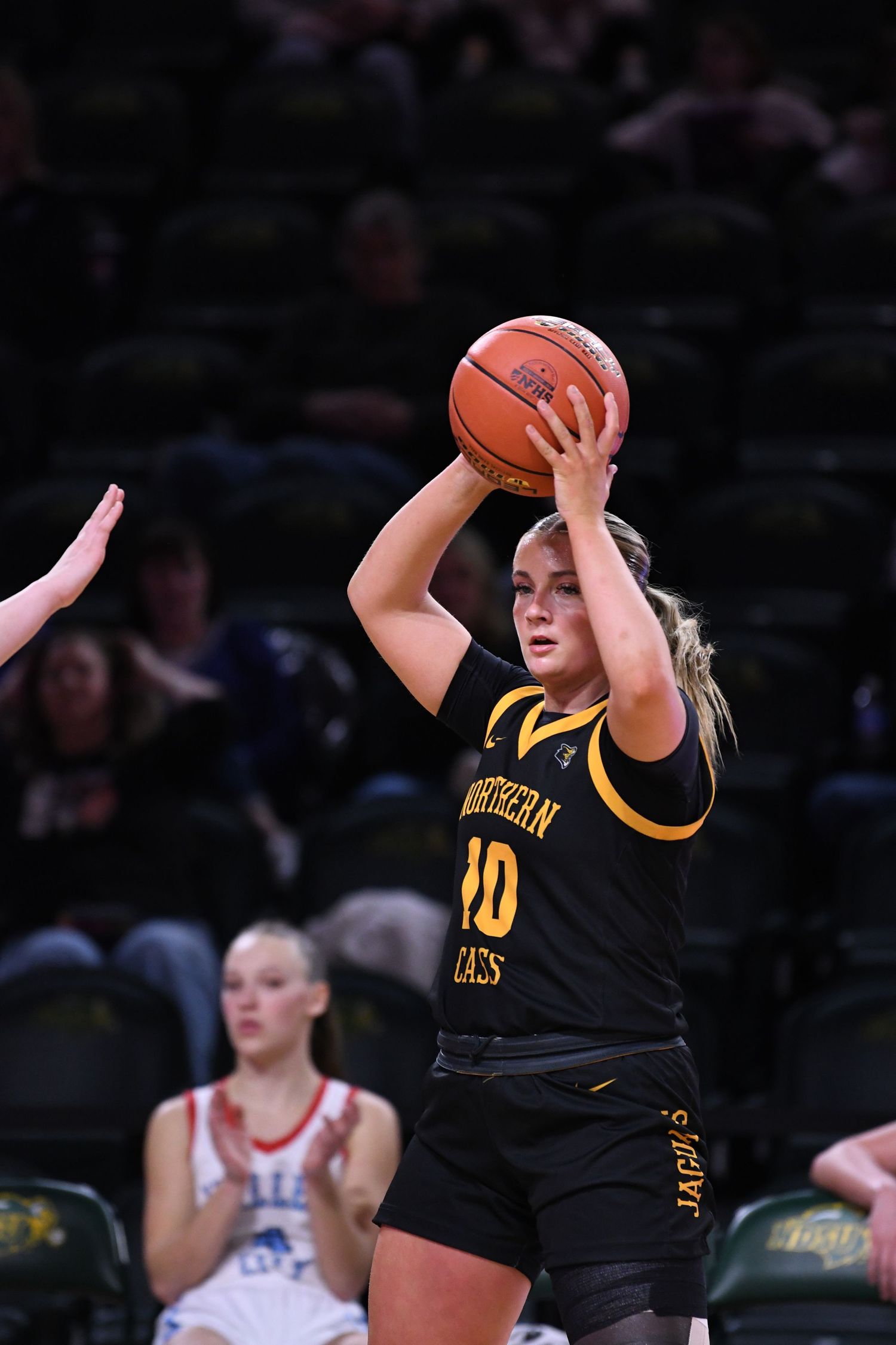 Player in black uniform takes a shot during basketball game.