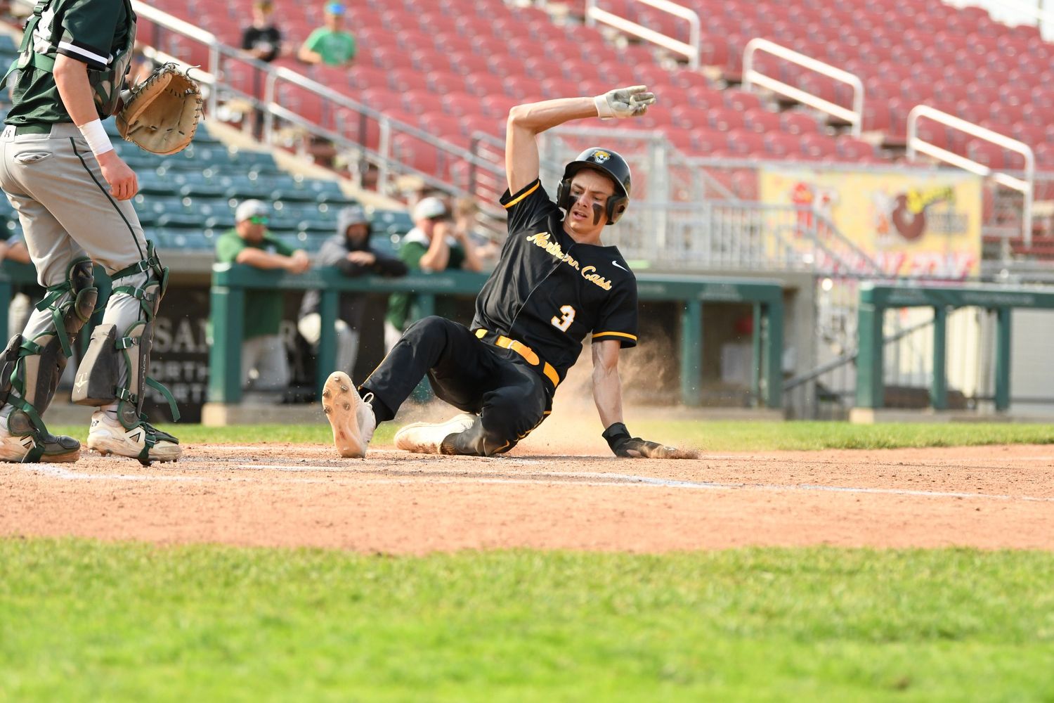 Baseball players executing sliding techniques on the baseball diamond during practice.