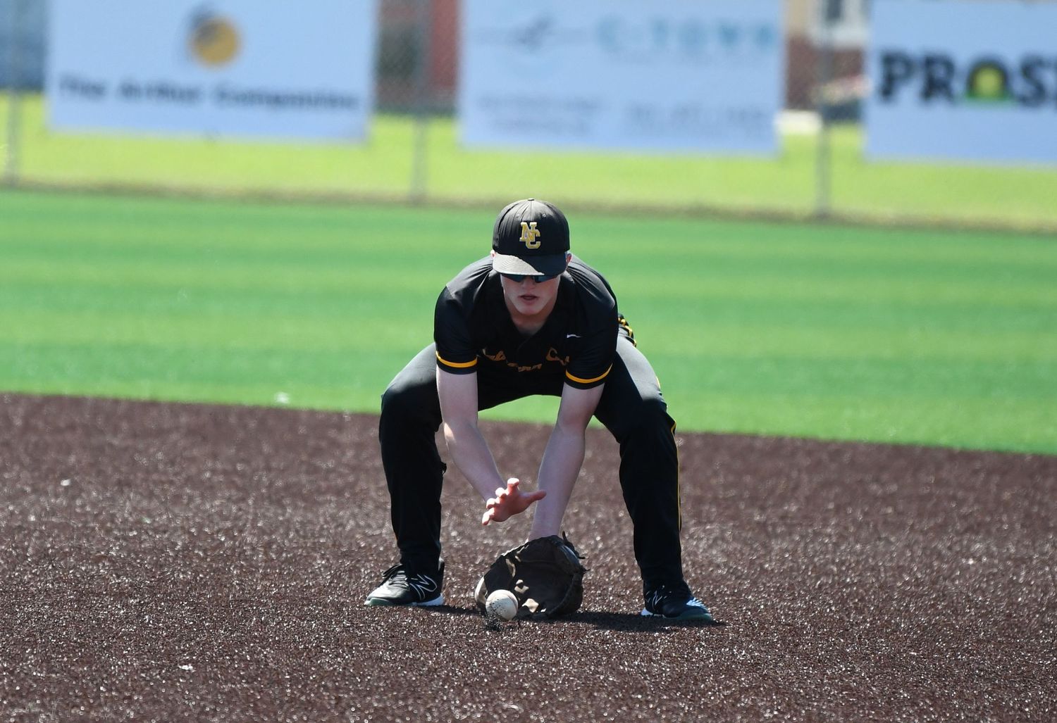Baseball infielder gets in position to field a ground ball on the dirt infield.