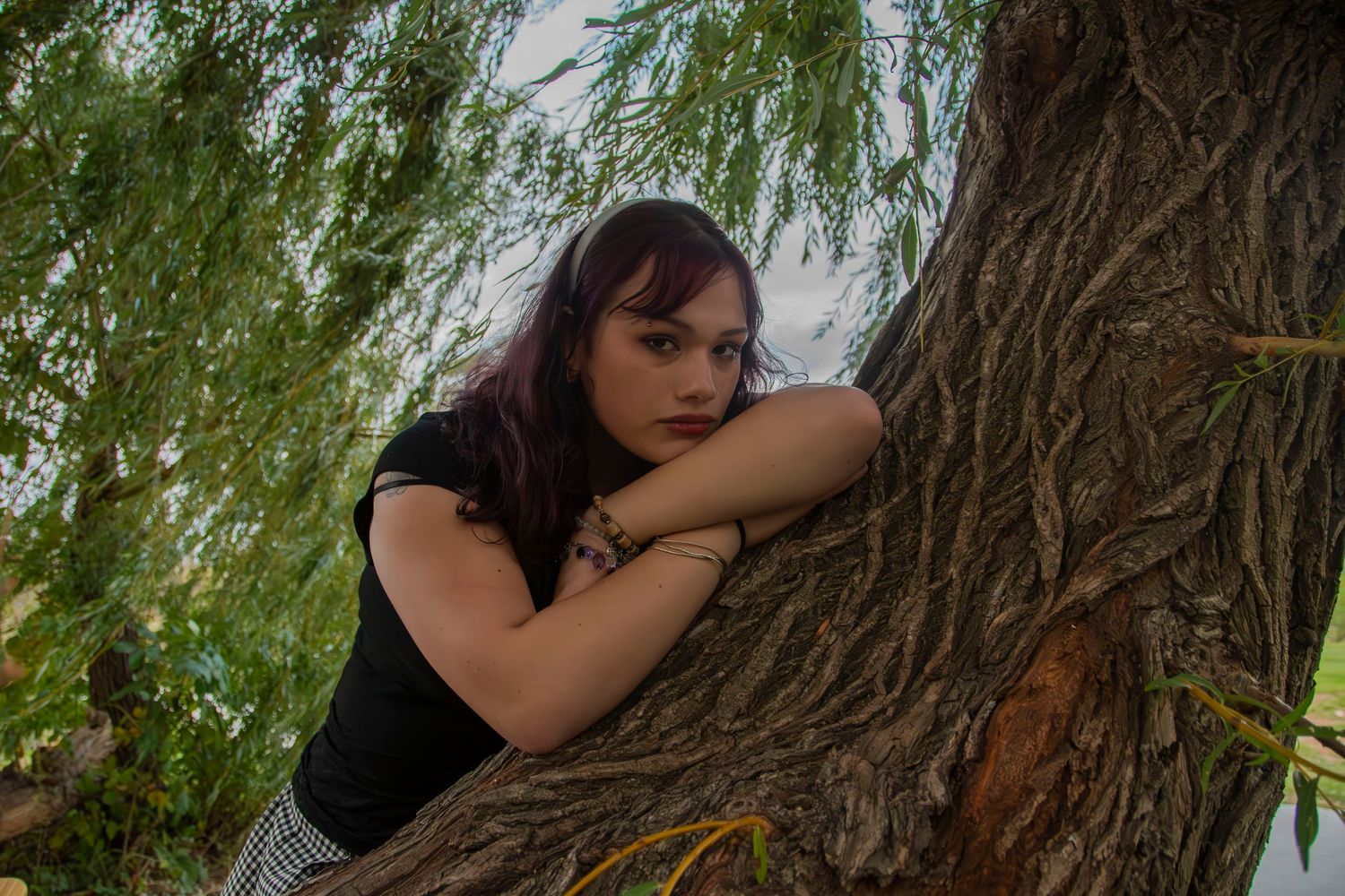 Person in black hugging a tree trunk in a natural outdoor setting.