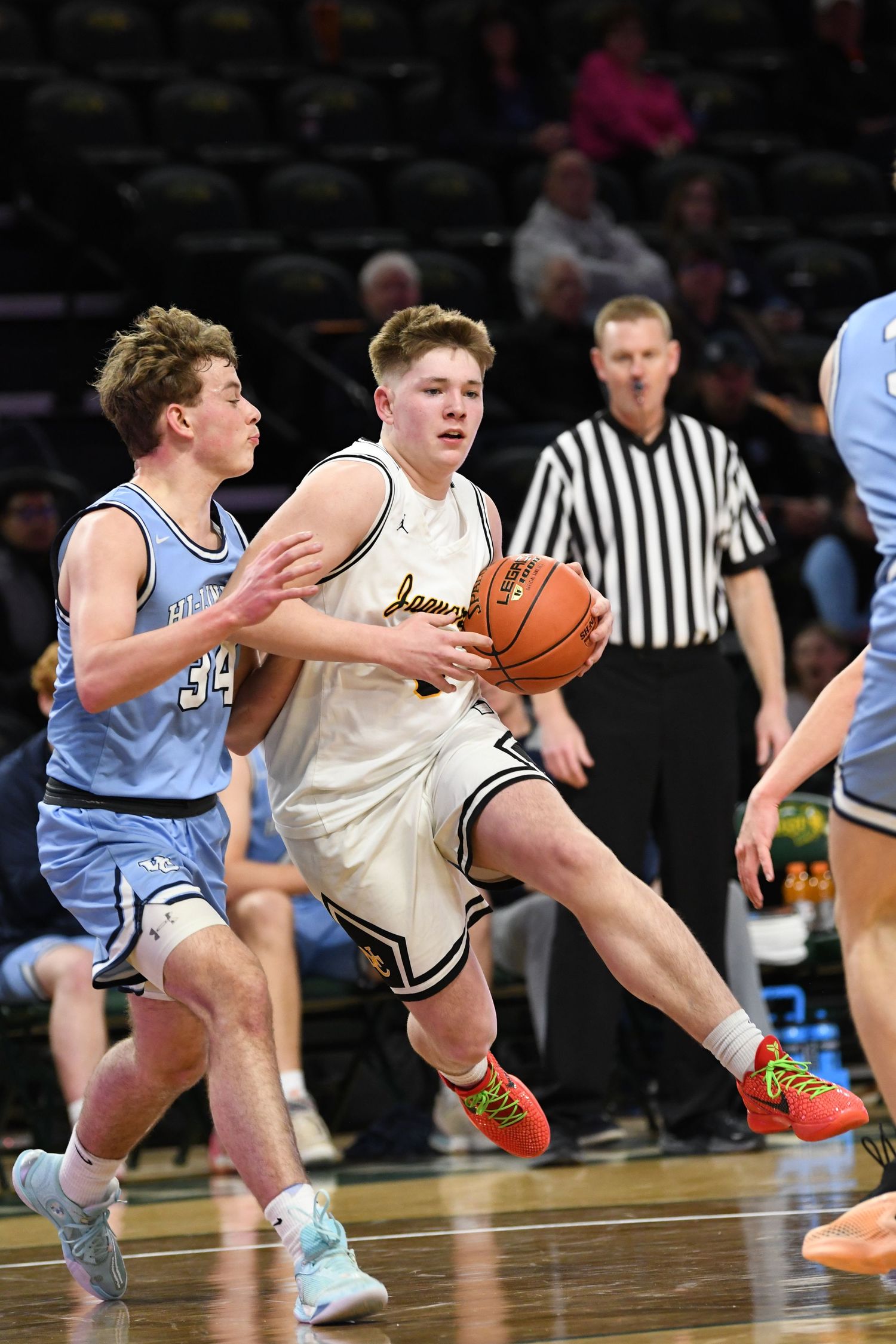 Basketball player drives through defense during competitive game action.