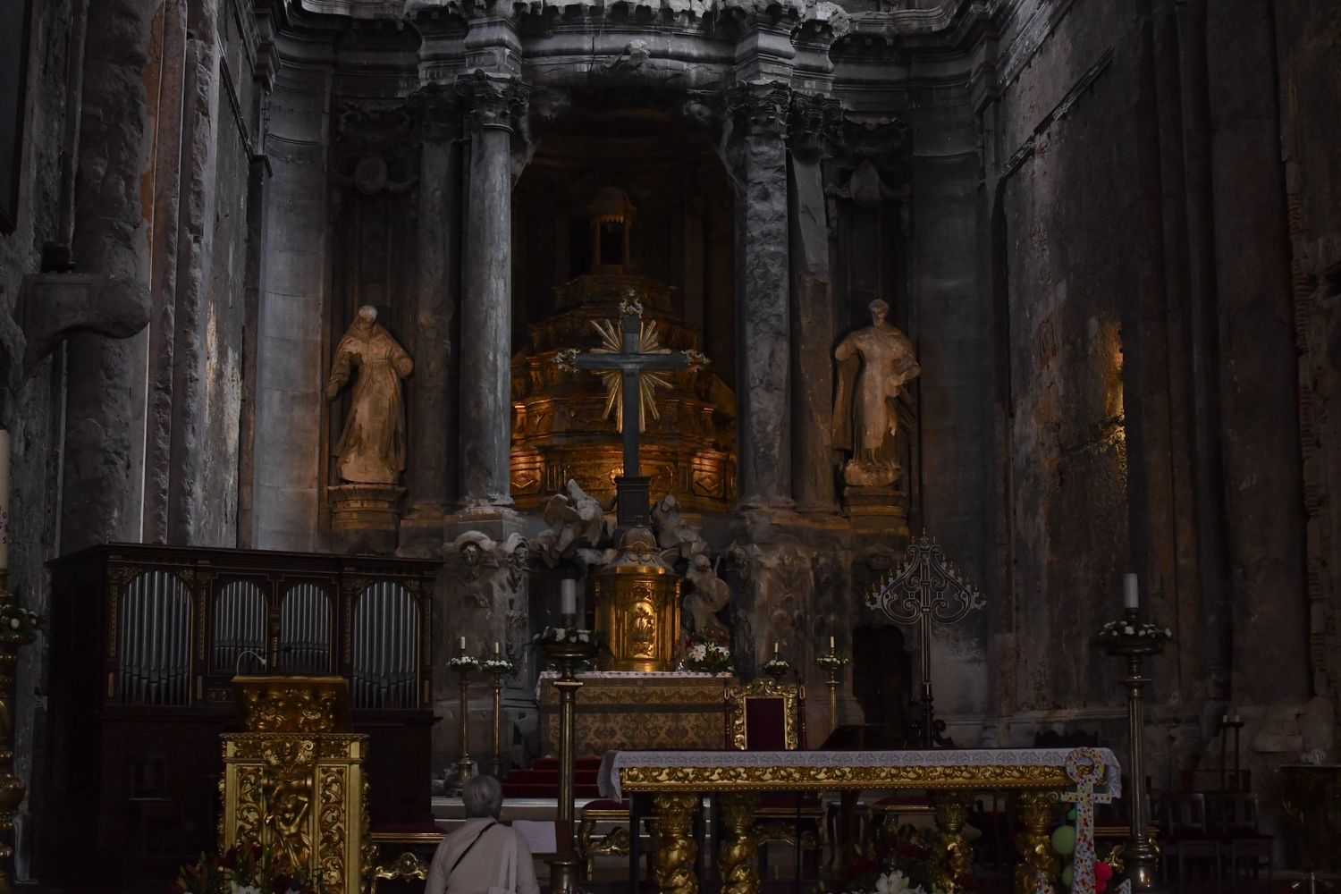 Dark gothic church altar with golden details and religious statues in dramatic lighting.