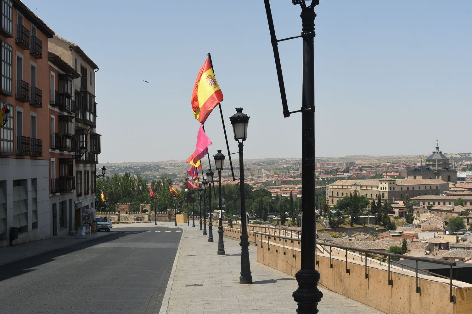 Spanish flags wave along a street lined with historic buildings and ornate lampposts.
