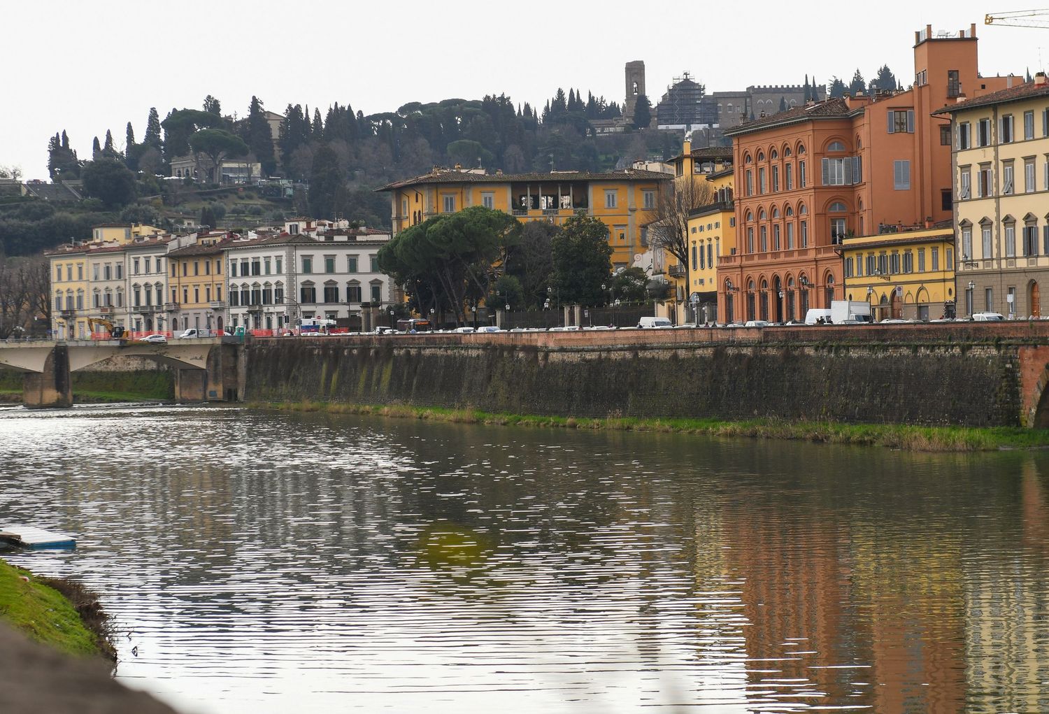 Panoramic view of historic buildings along a waterfront with reflections in calm water.