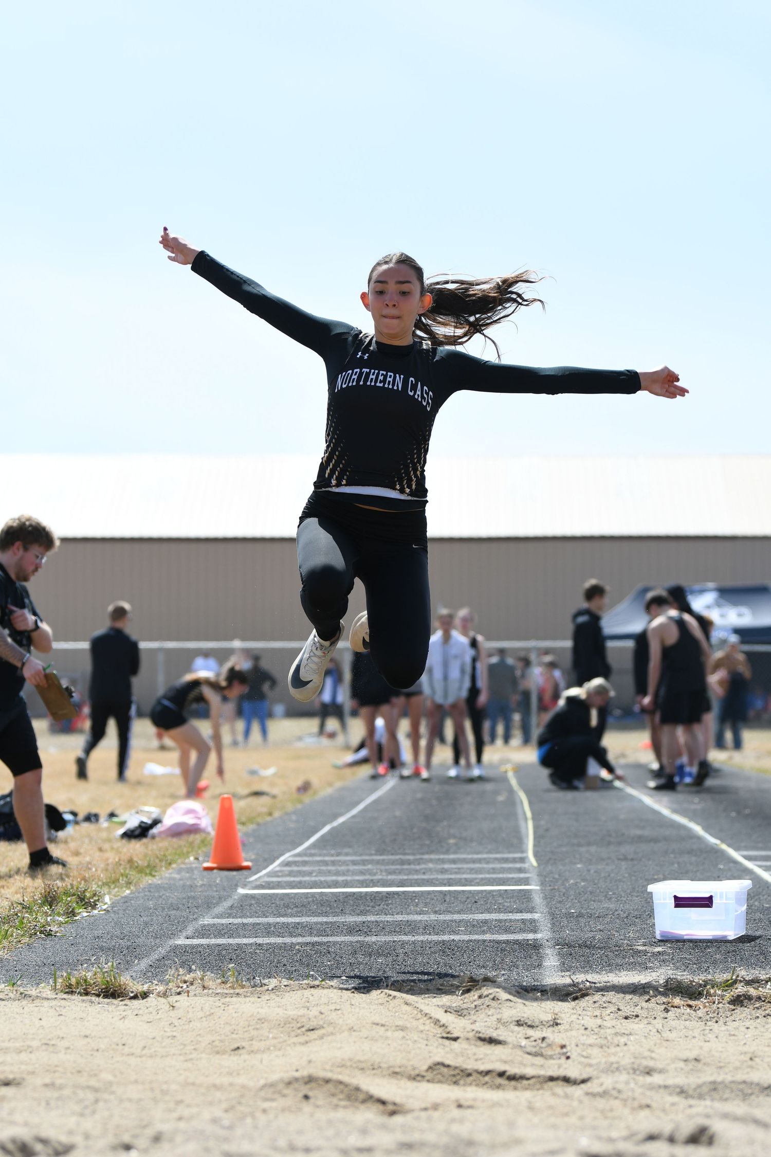 Athletes perform triple jump sequences on an outdoor track during competition.