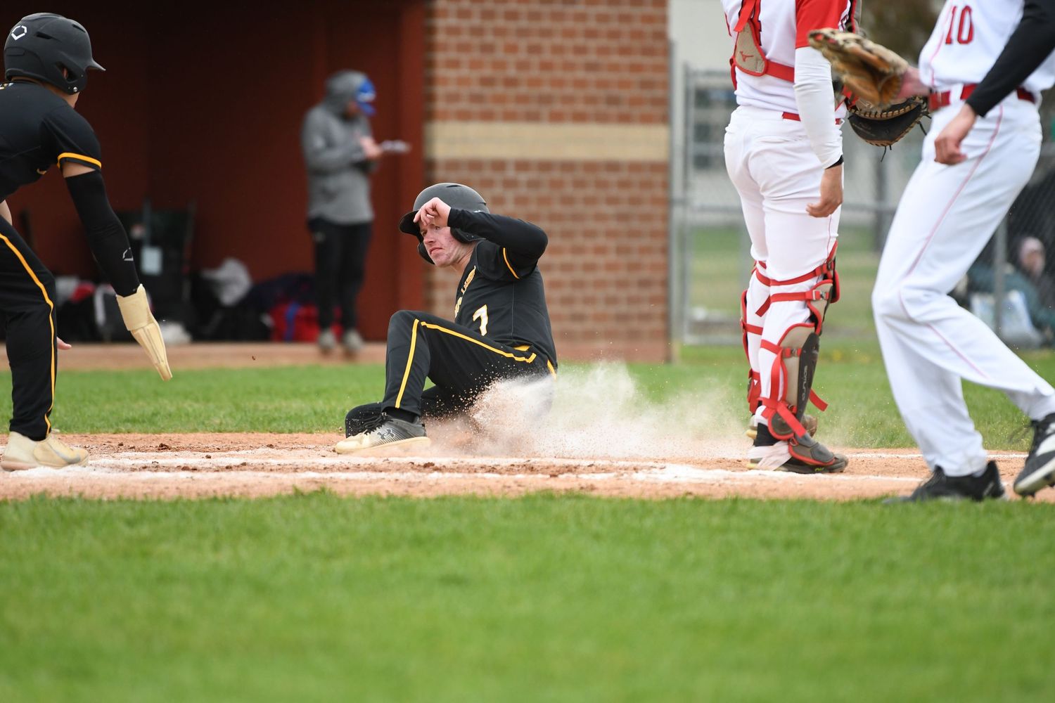 Baseball action shot showing dust cloud near base during competitive play.