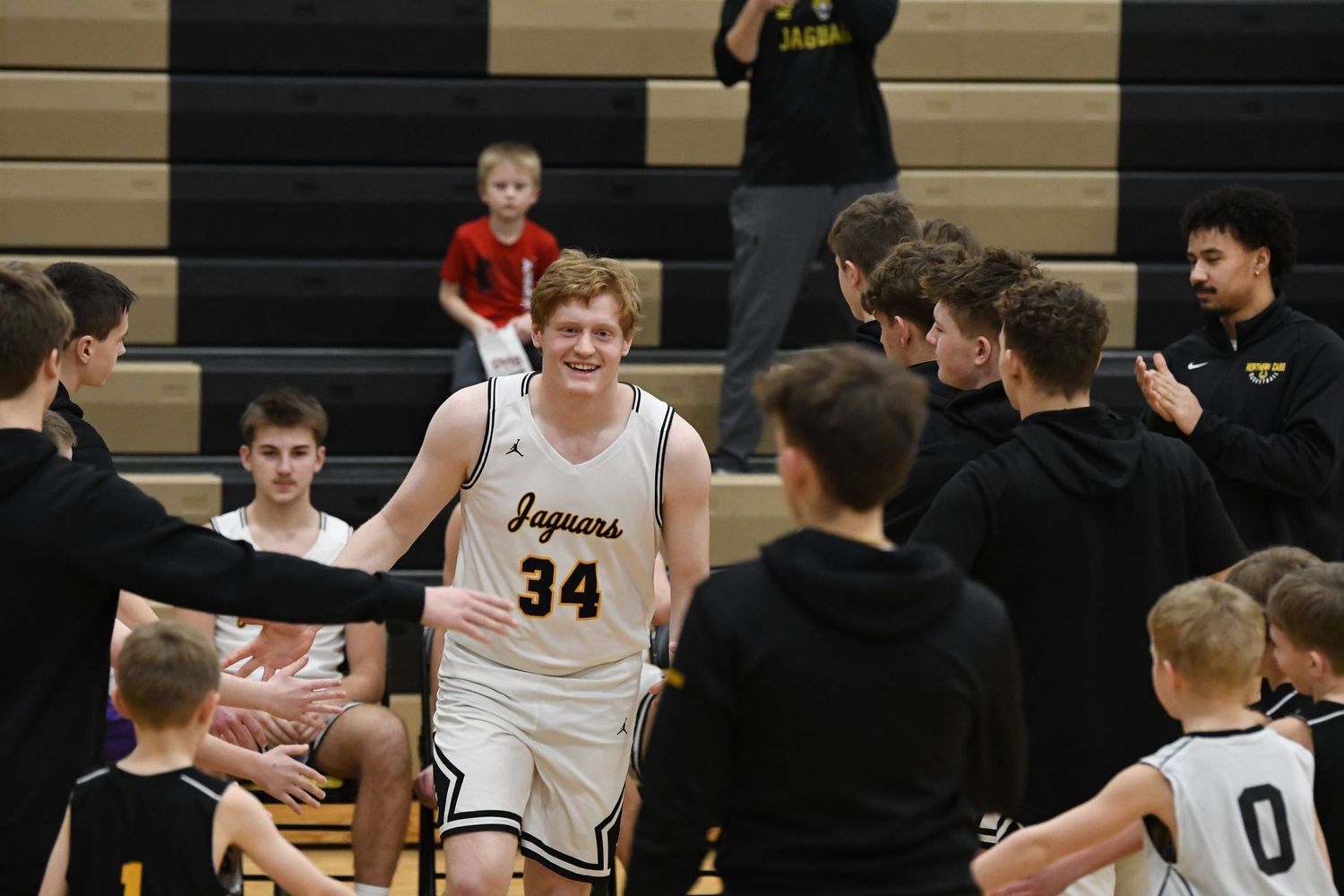 Basketball player in white Jaguars jersey greets supporters after the game.